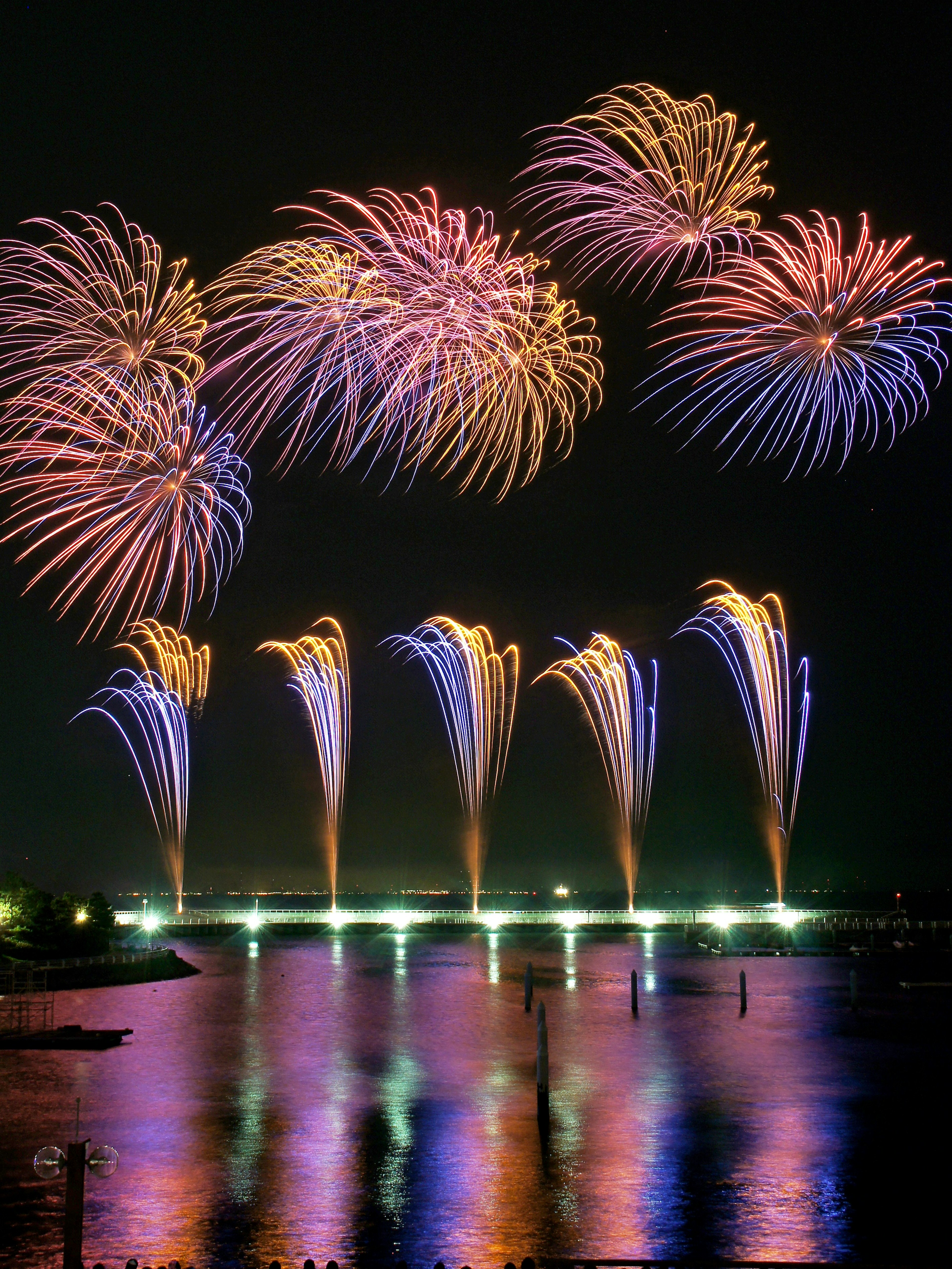 Vibrant fireworks display lighting up the night sky reflections on the water surface