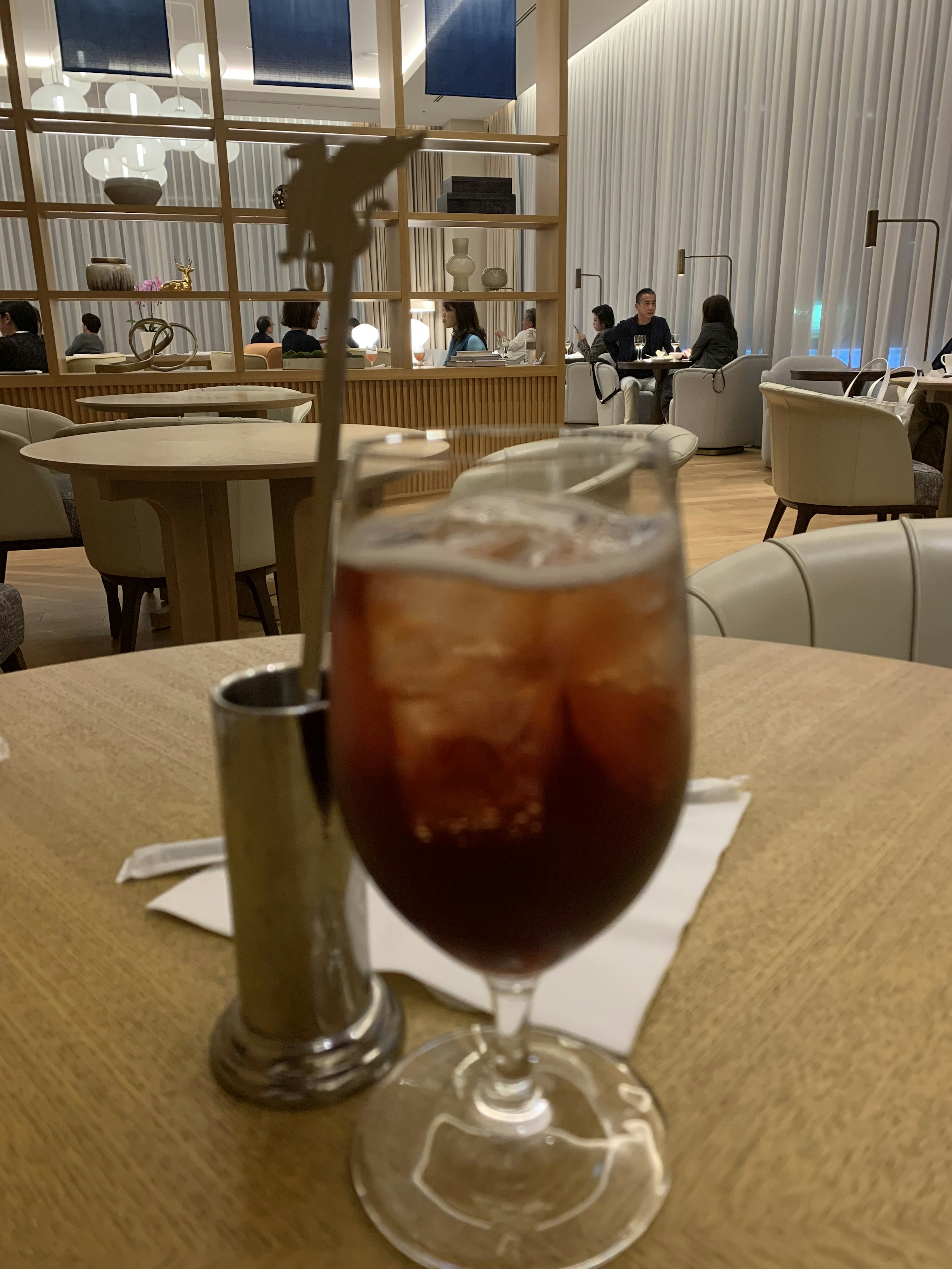 Vaso de té helado sobre una mesa con una pajita de plata