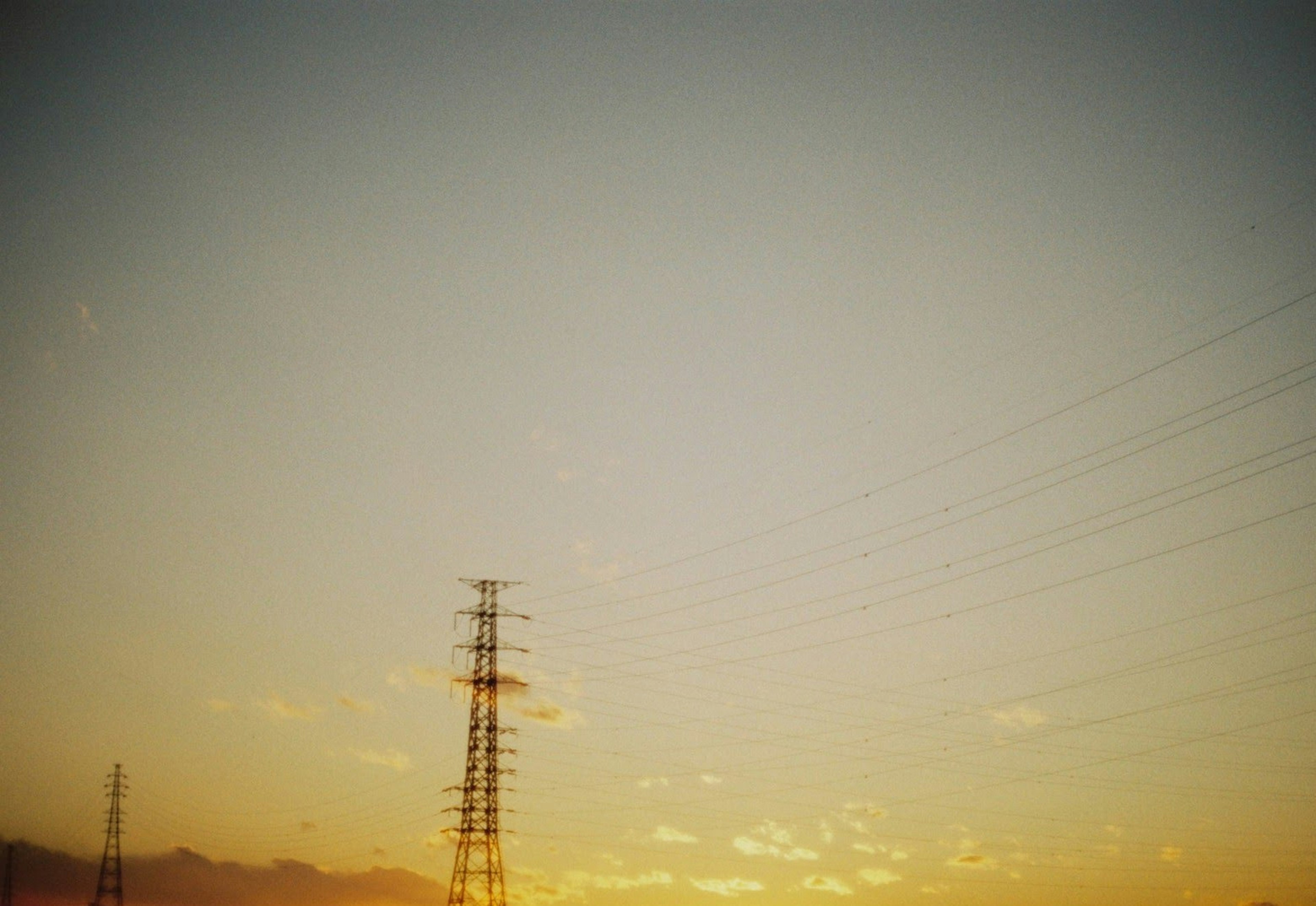 Silhouette of power poles against a sunset sky