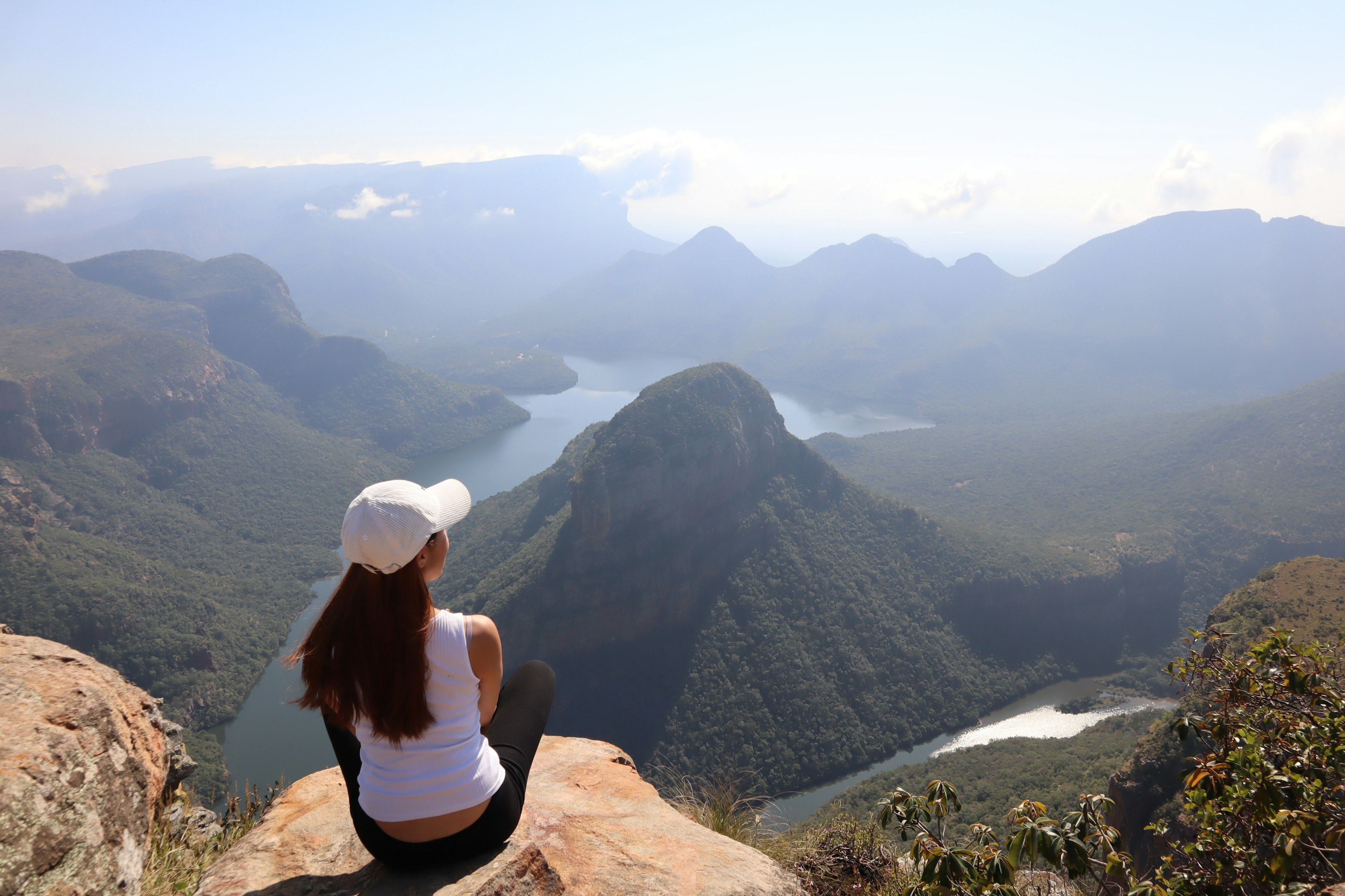 Mujer sentada en una roca mirando un impresionante paisaje montañoso