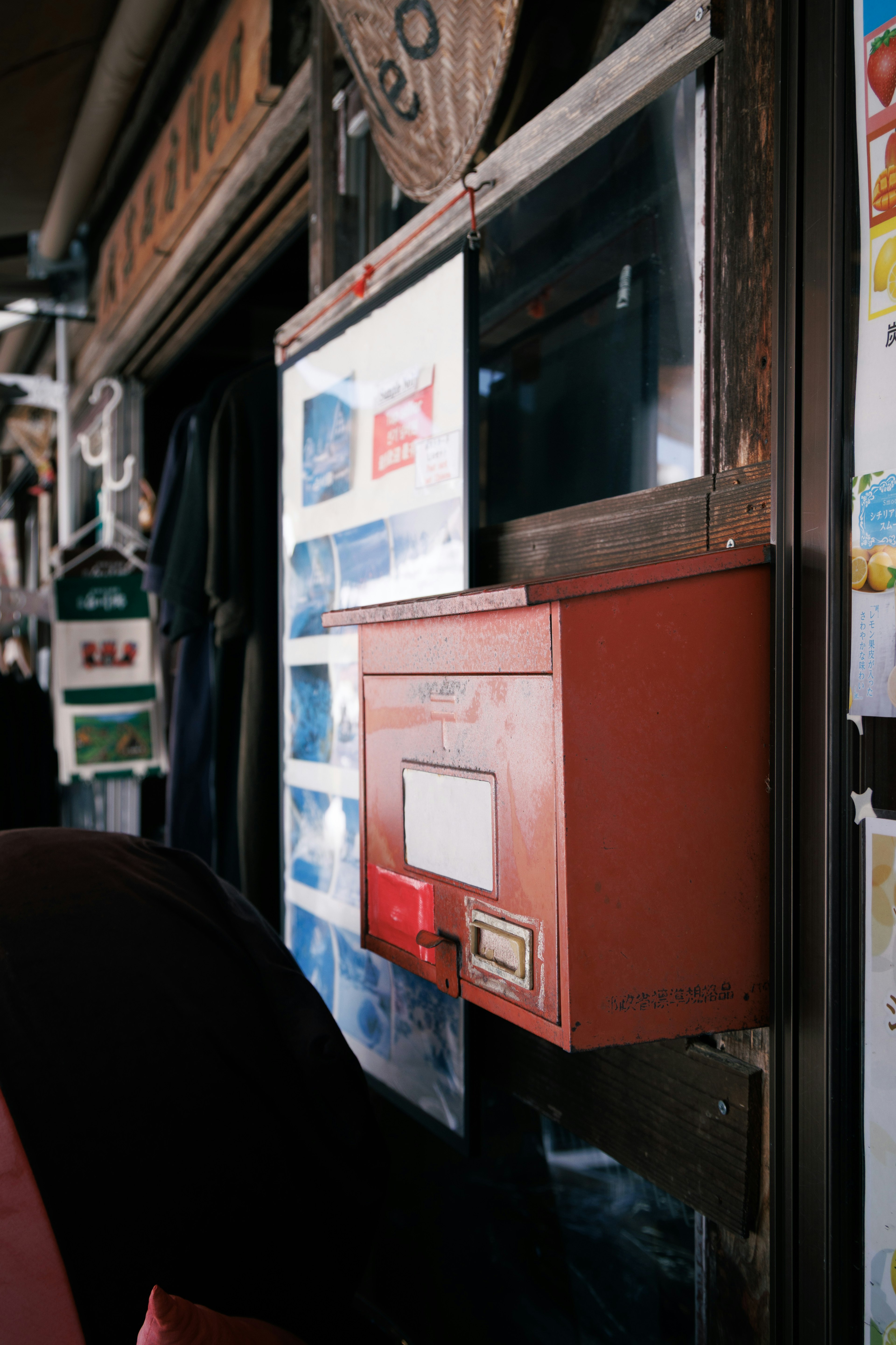 Boîte aux lettres rouge à côté de vitrines avec des distributeurs automatiques