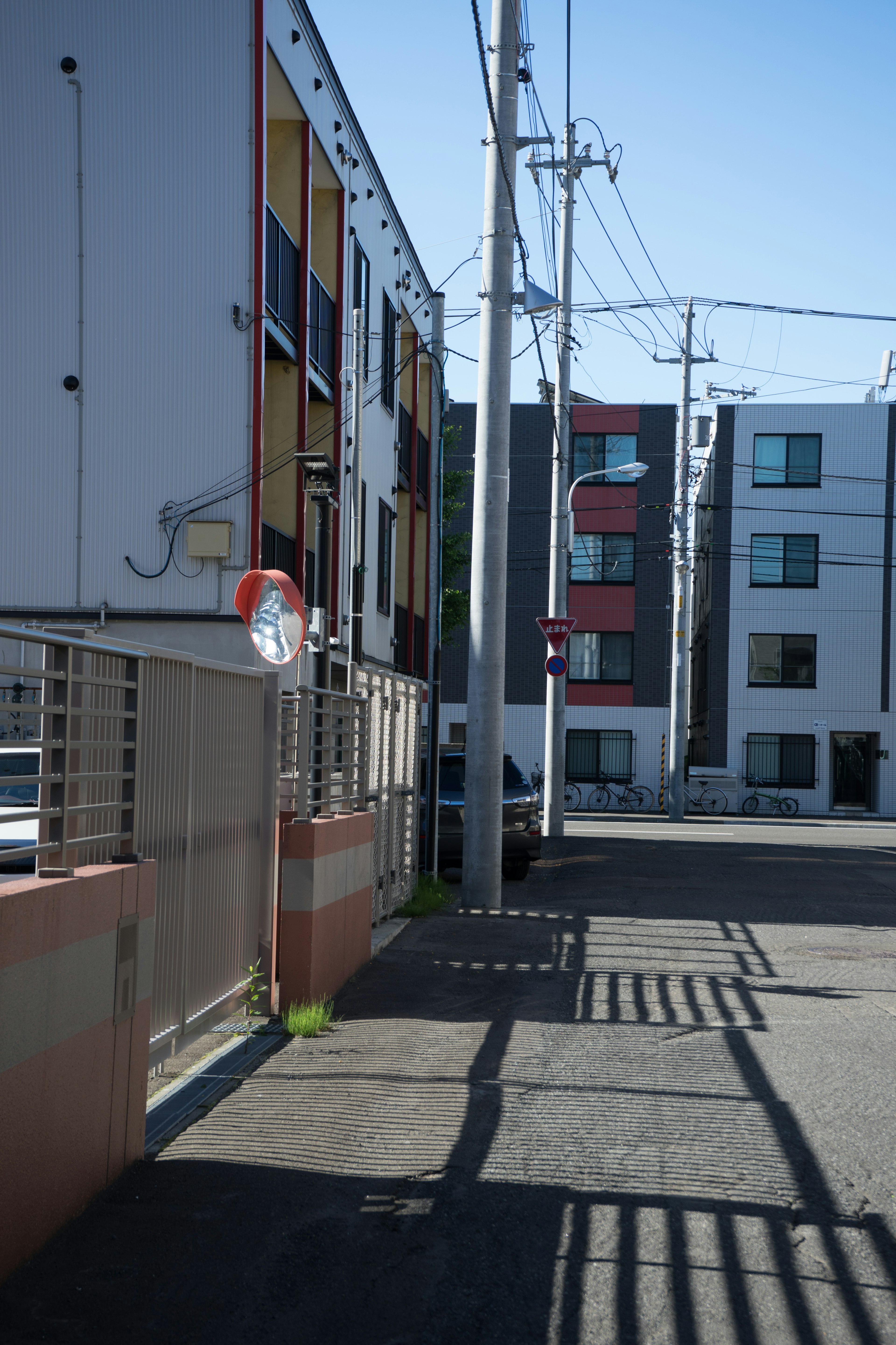 Vista di una strada in un'area residenziale sotto un cielo blu brillante con edifici colorati e pali della luce