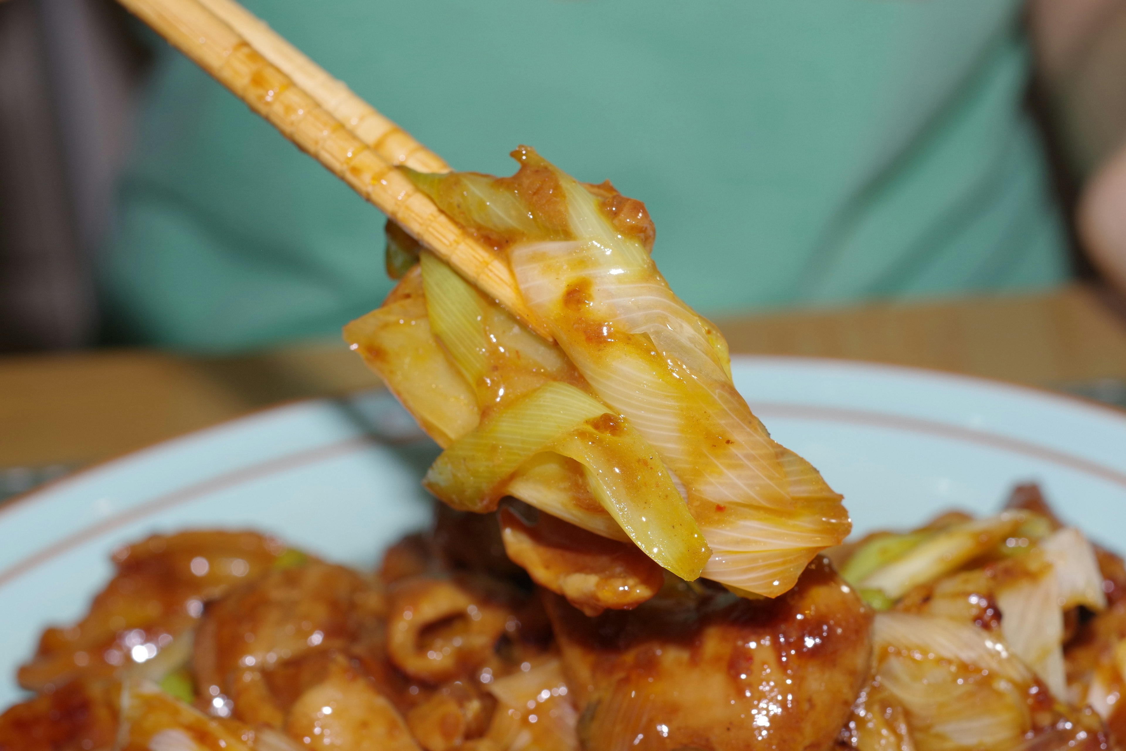 A piece of sweet and savory cabbage dish held by chopsticks