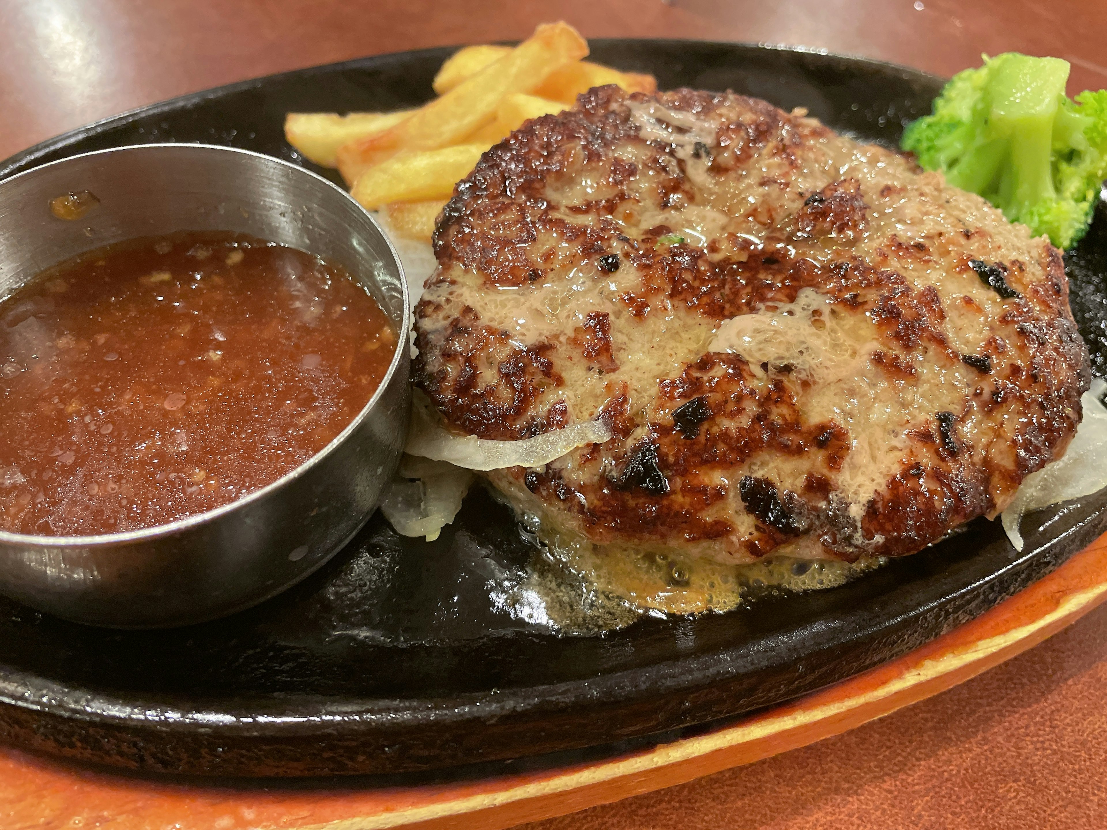 Zischendes Hamburgersteak mit Pommes und Sauce