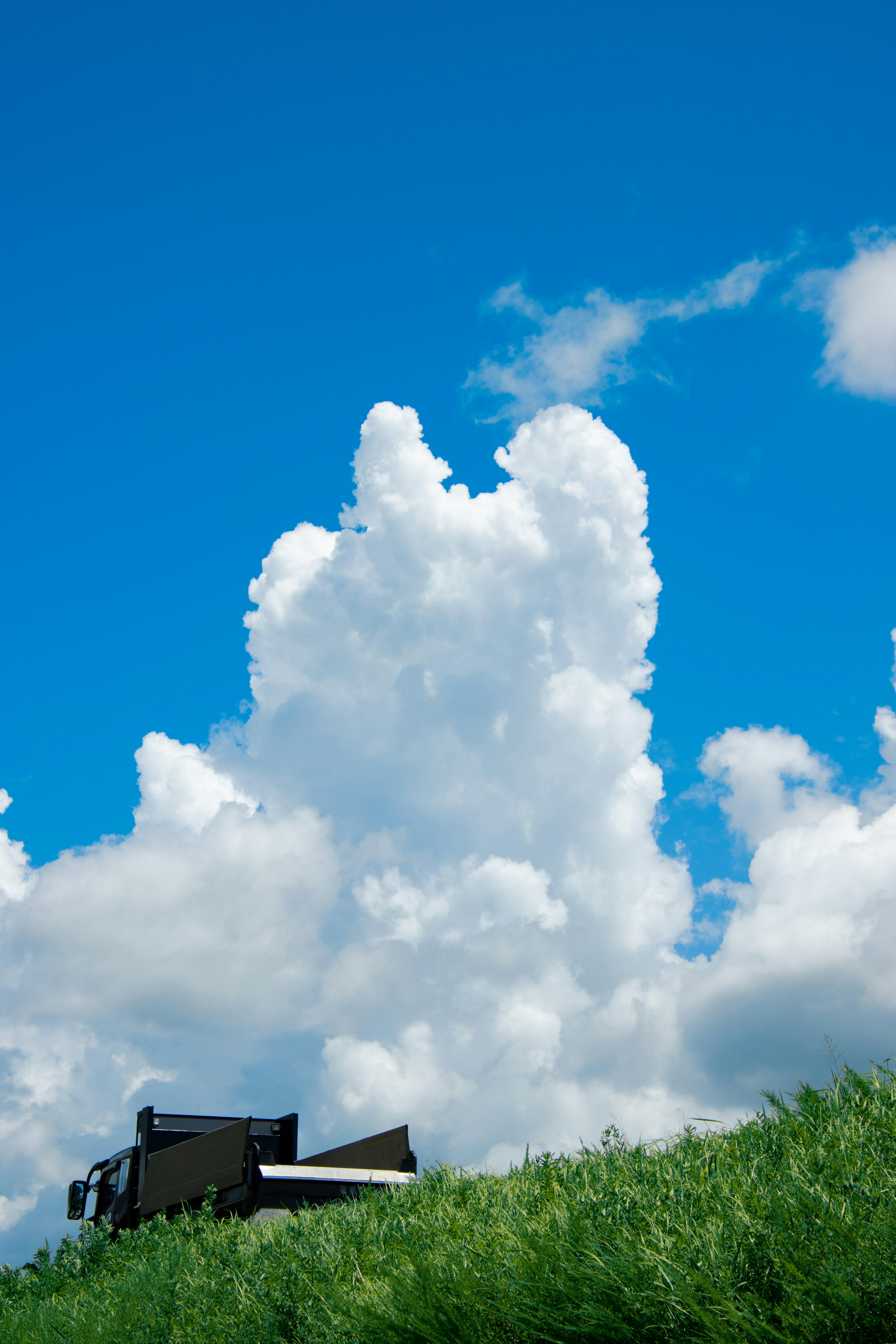 Machinerie noire sur herbe verte sous un ciel bleu clair avec des nuages blancs duveteux