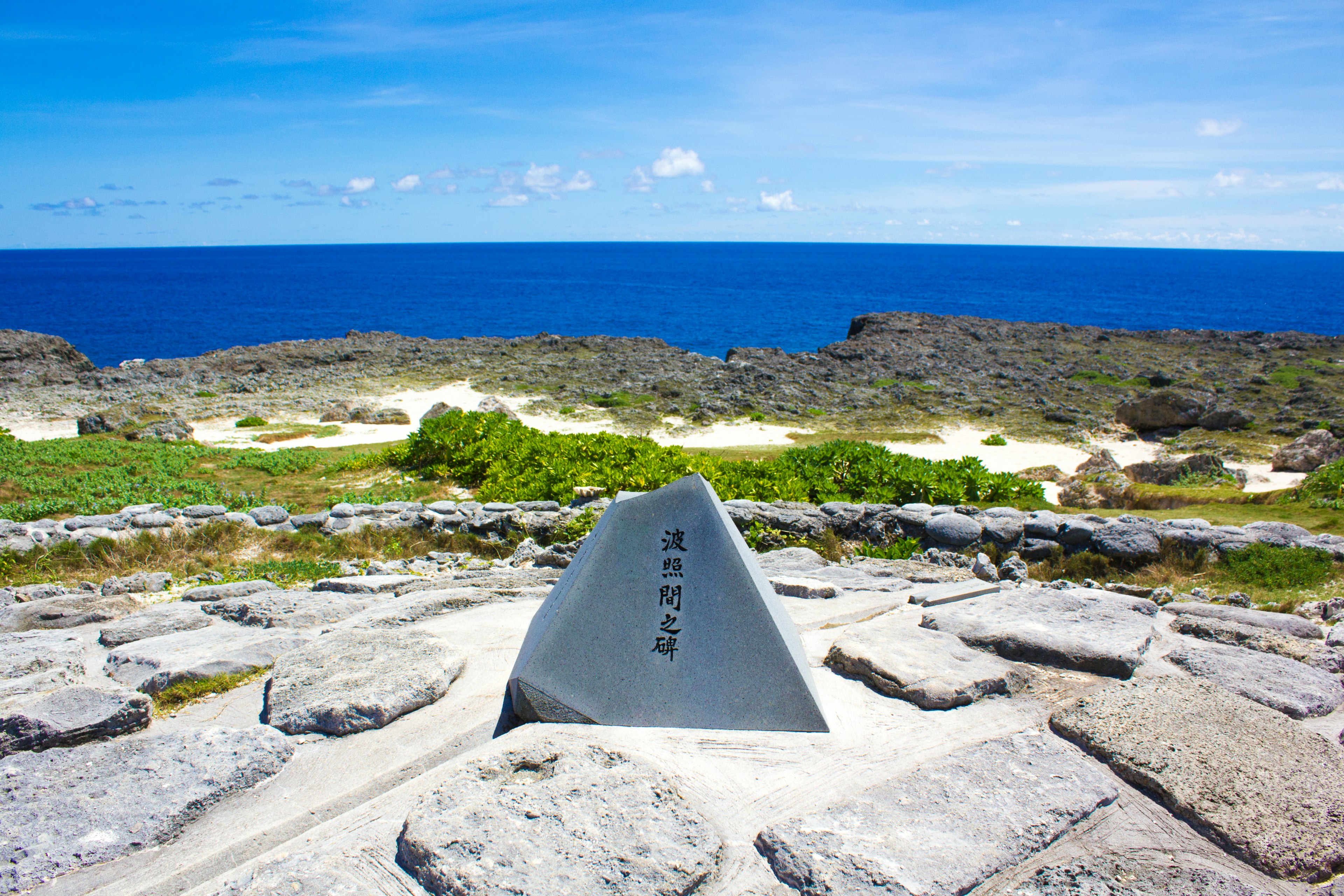 Steinmonument mit Blick auf einen blauen Ozean und eine grüne Landschaft