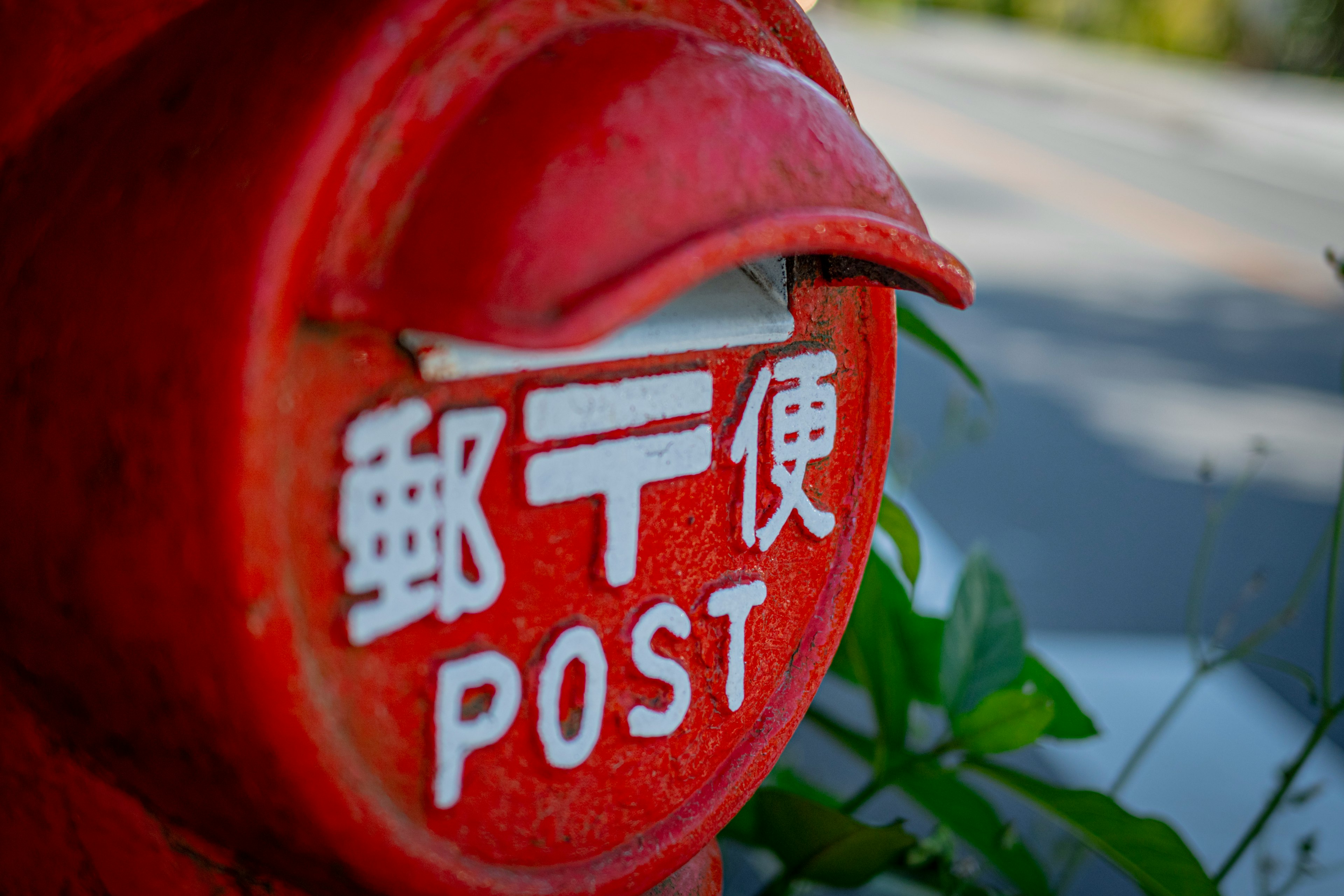 Red mailbox featuring white lettering that reads Postal and POST