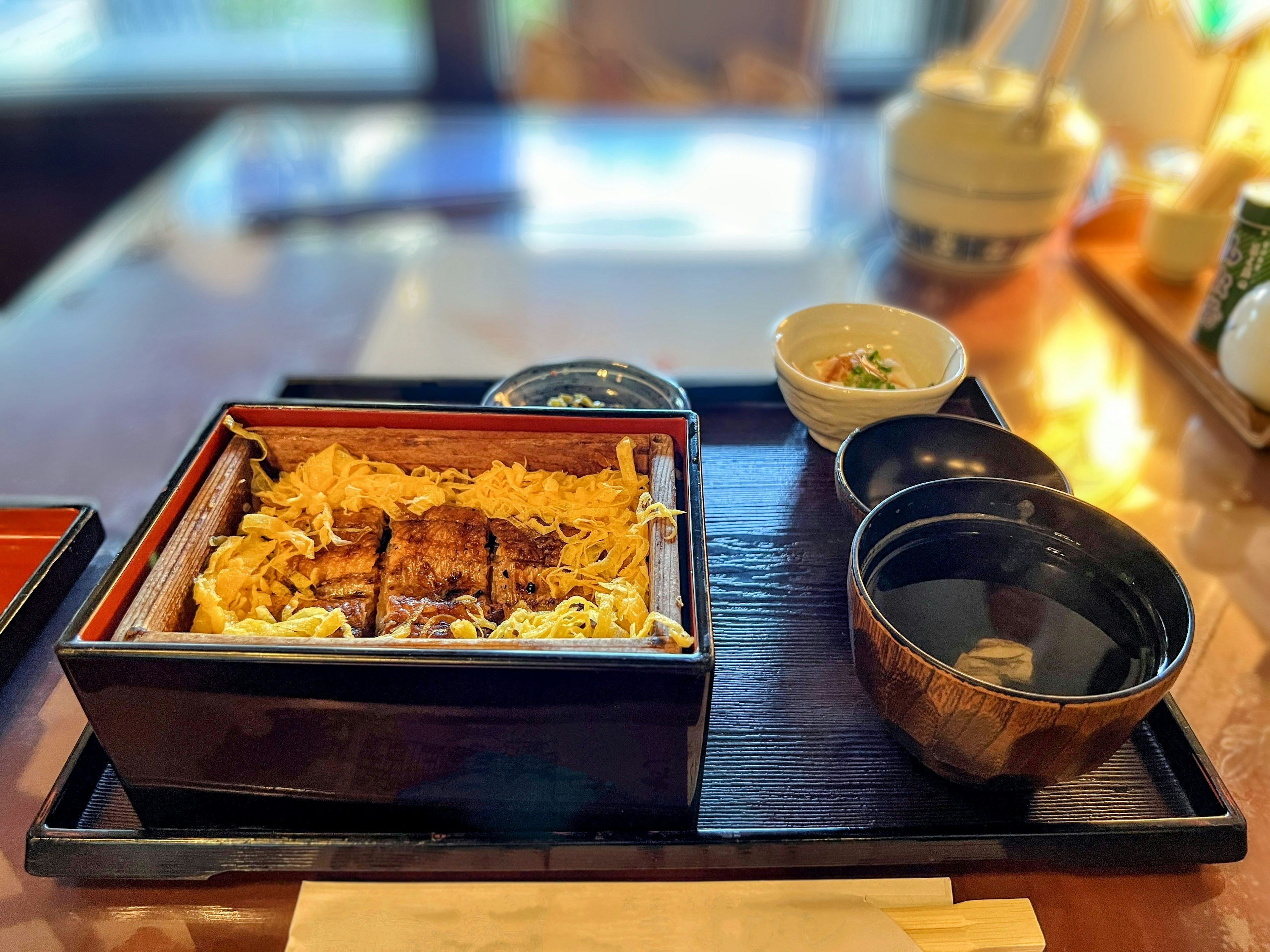 Un délicieux unaju servi dans une boîte en bois noir traditionnelle avec des plats d'accompagnement