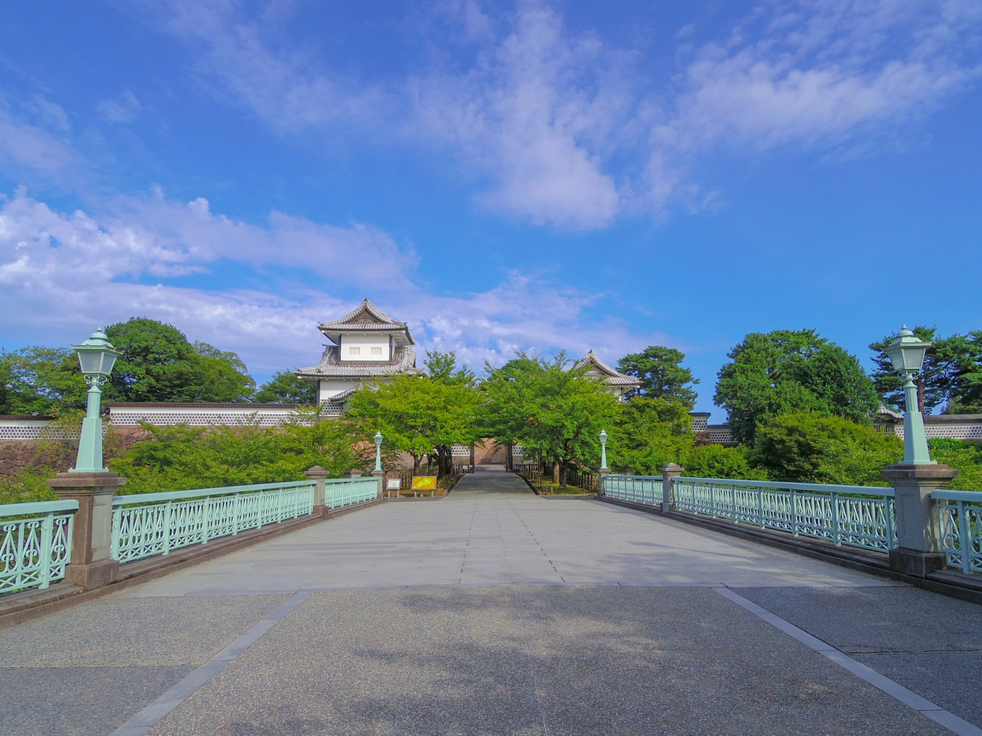 สะพานสวยงามนำไปสู่ปราสาทที่ล้อมรอบด้วยความเขียวขจีและท้องฟ้าสีฟ้า