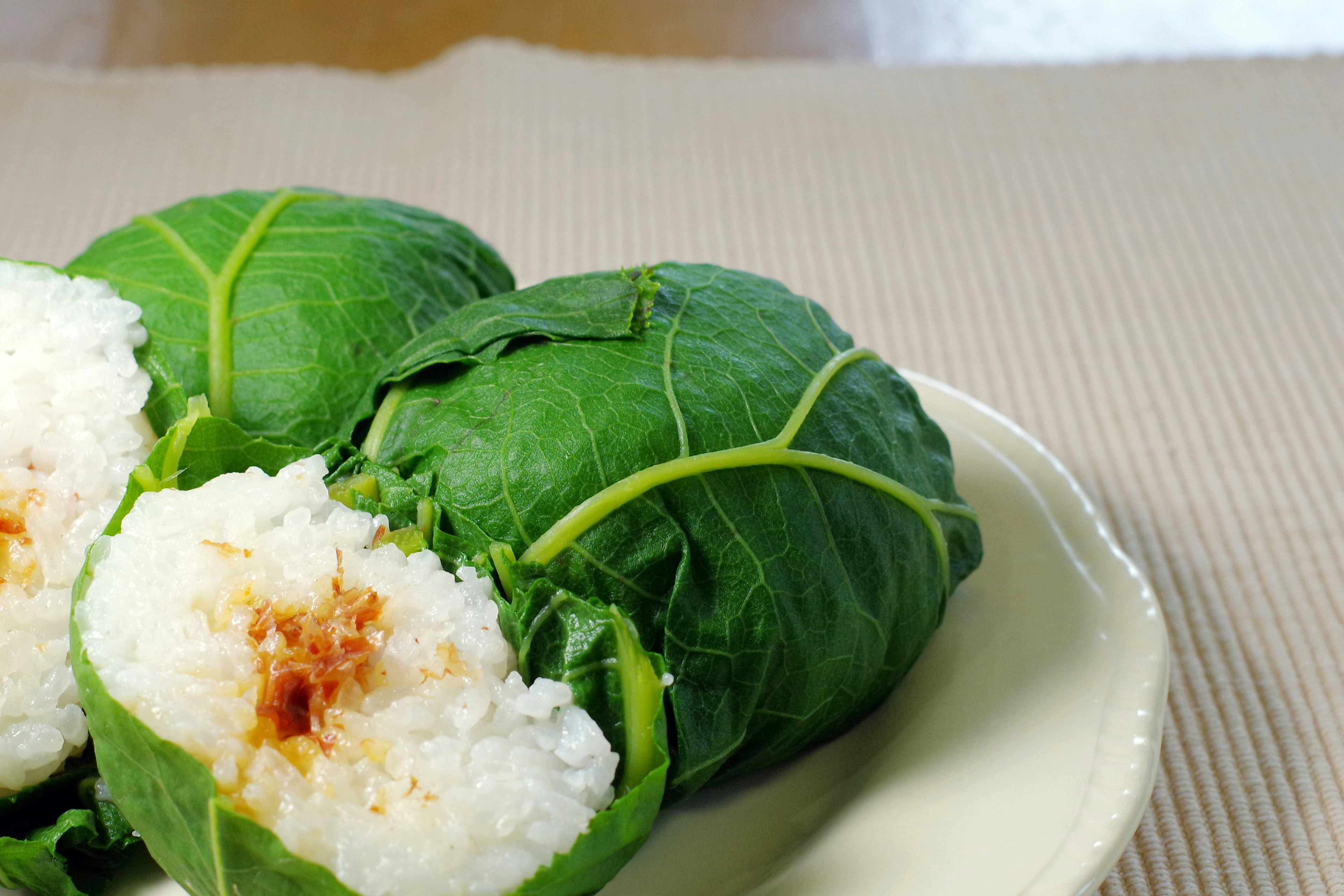 Bola nasi yang dibungkus daun hijau di atas piring