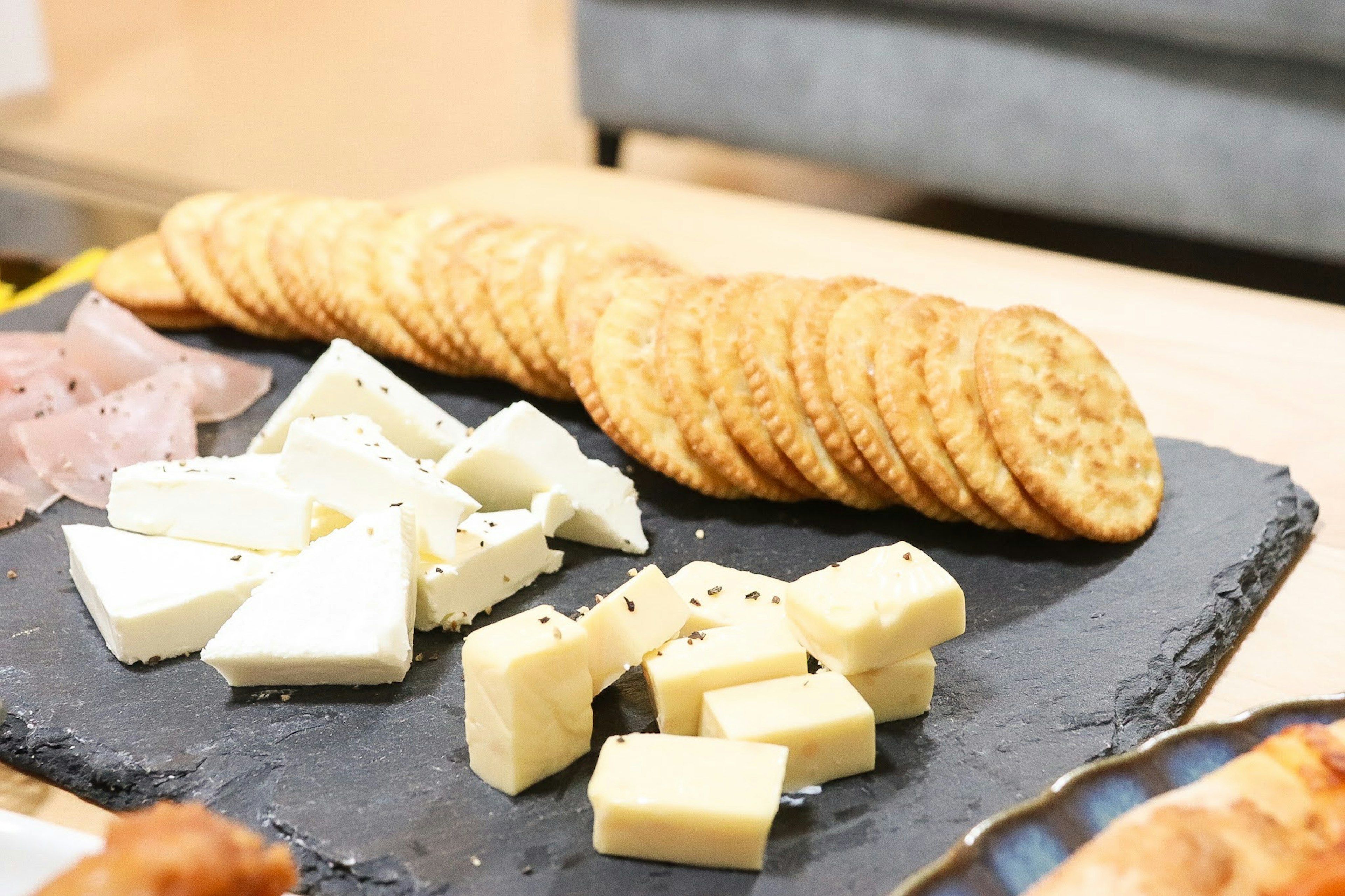 Piatto di formaggi e cracker disposto su un piatto di pietra nera