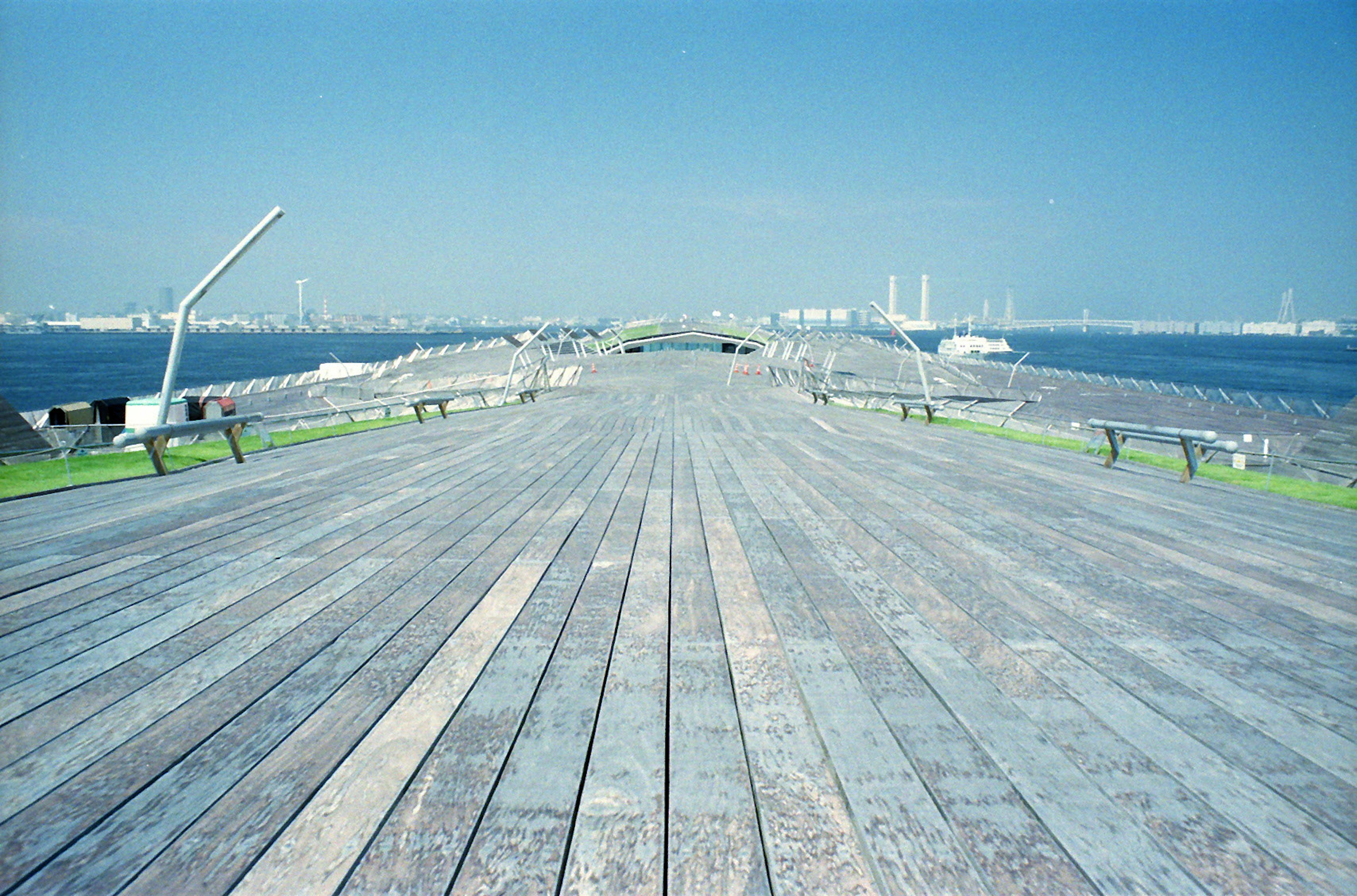 Breite Holzterrasse umgeben von blauem Himmel und Meer