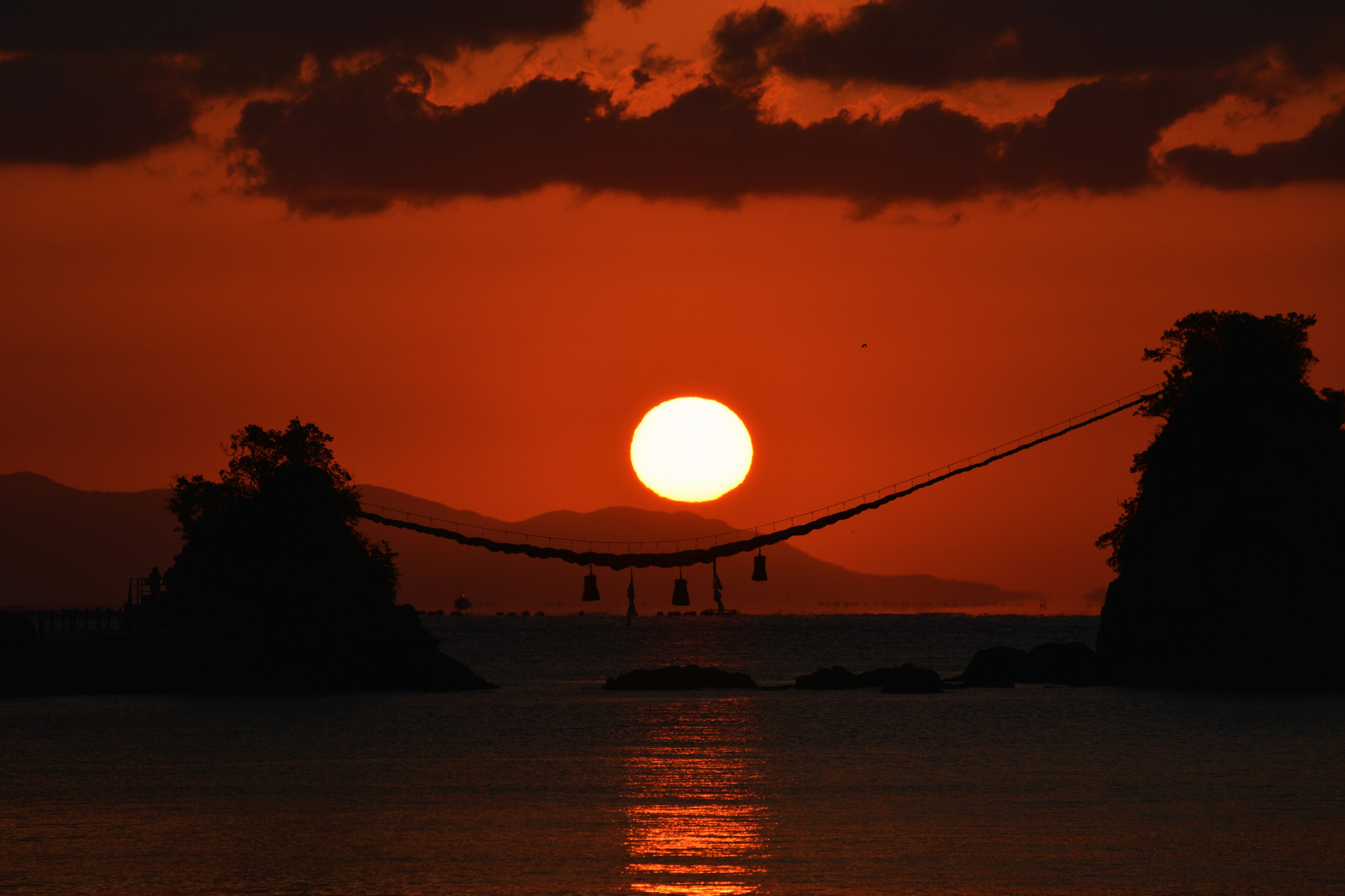 夕日が美しいオレンジ色に染まる海の風景 橋に吊るされた灯りが印象的