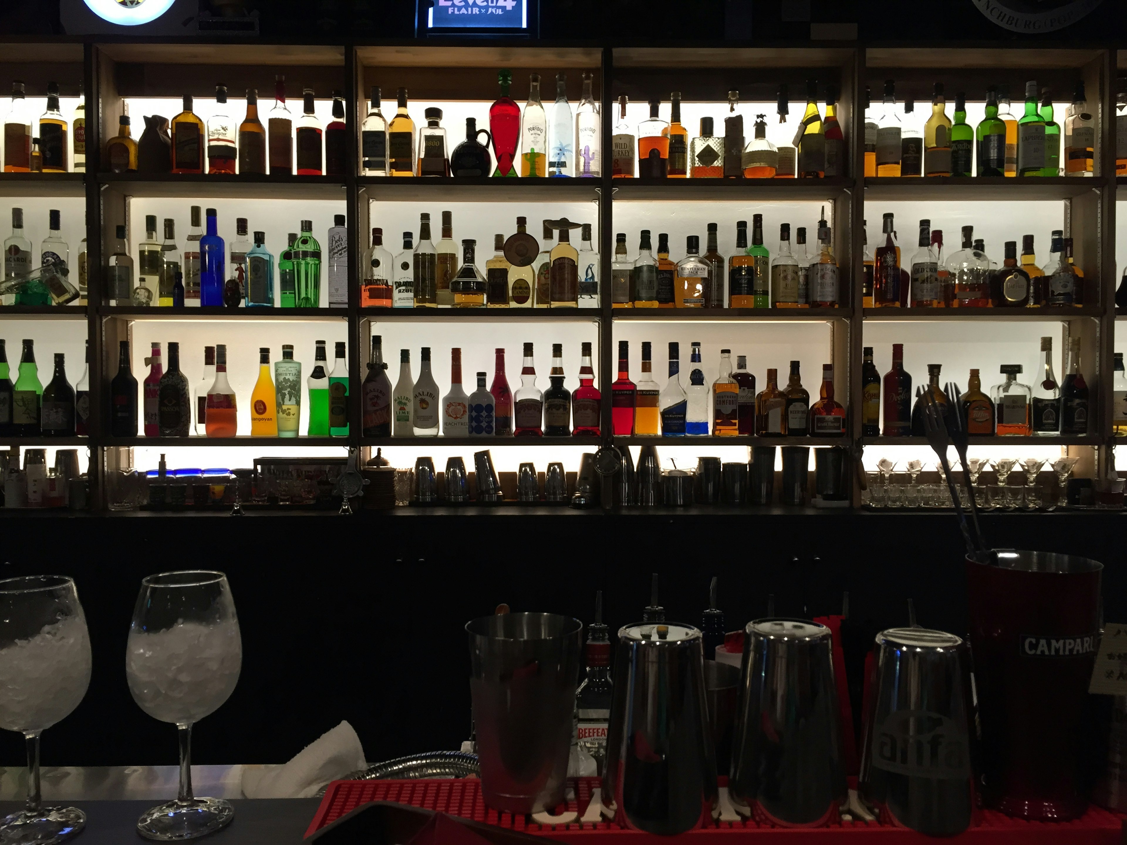 A bar shelf displaying a variety of liquor bottles and cocktail glasses