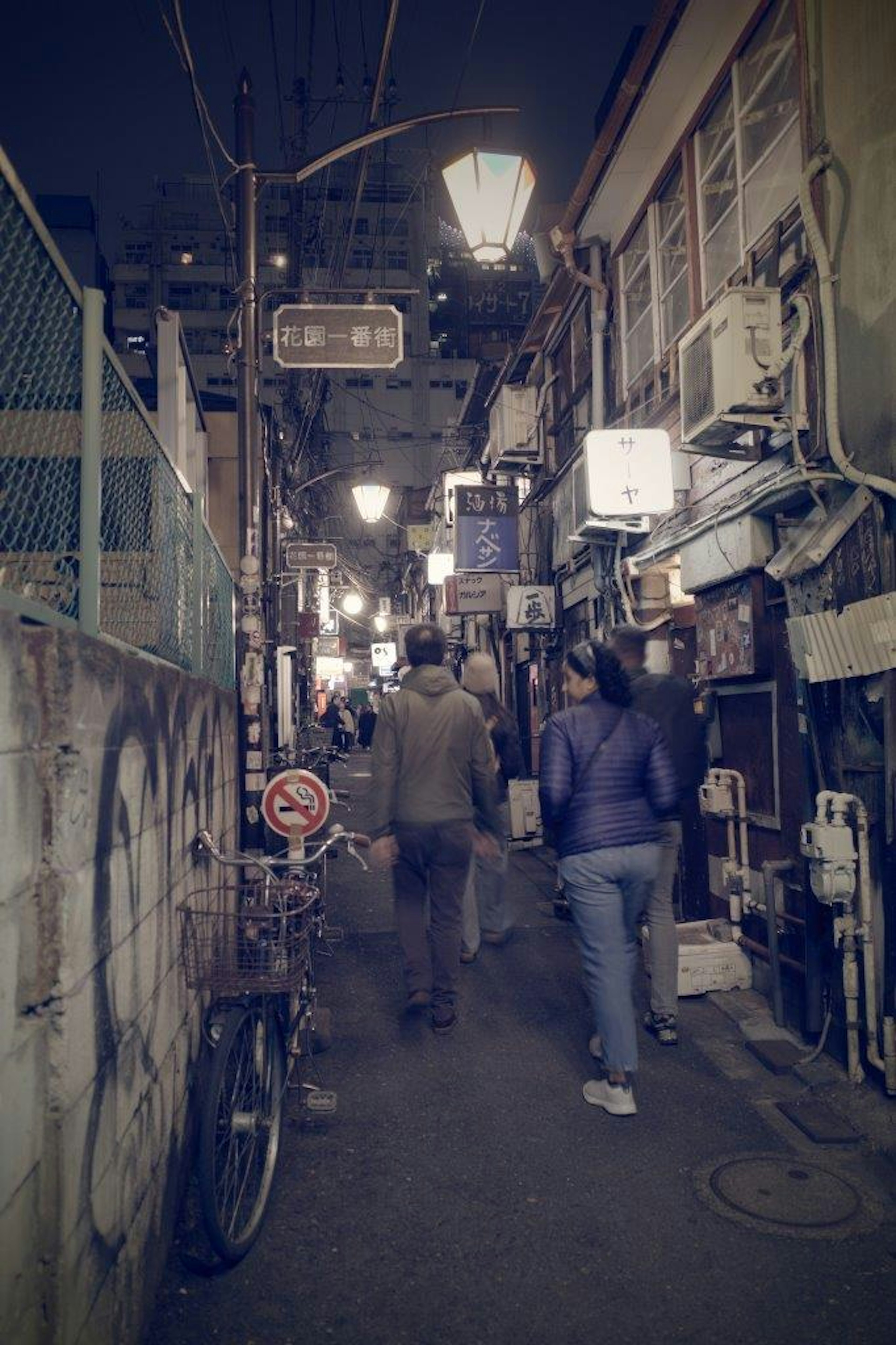 夜の東京の狭い路地に人々が歩いている風景