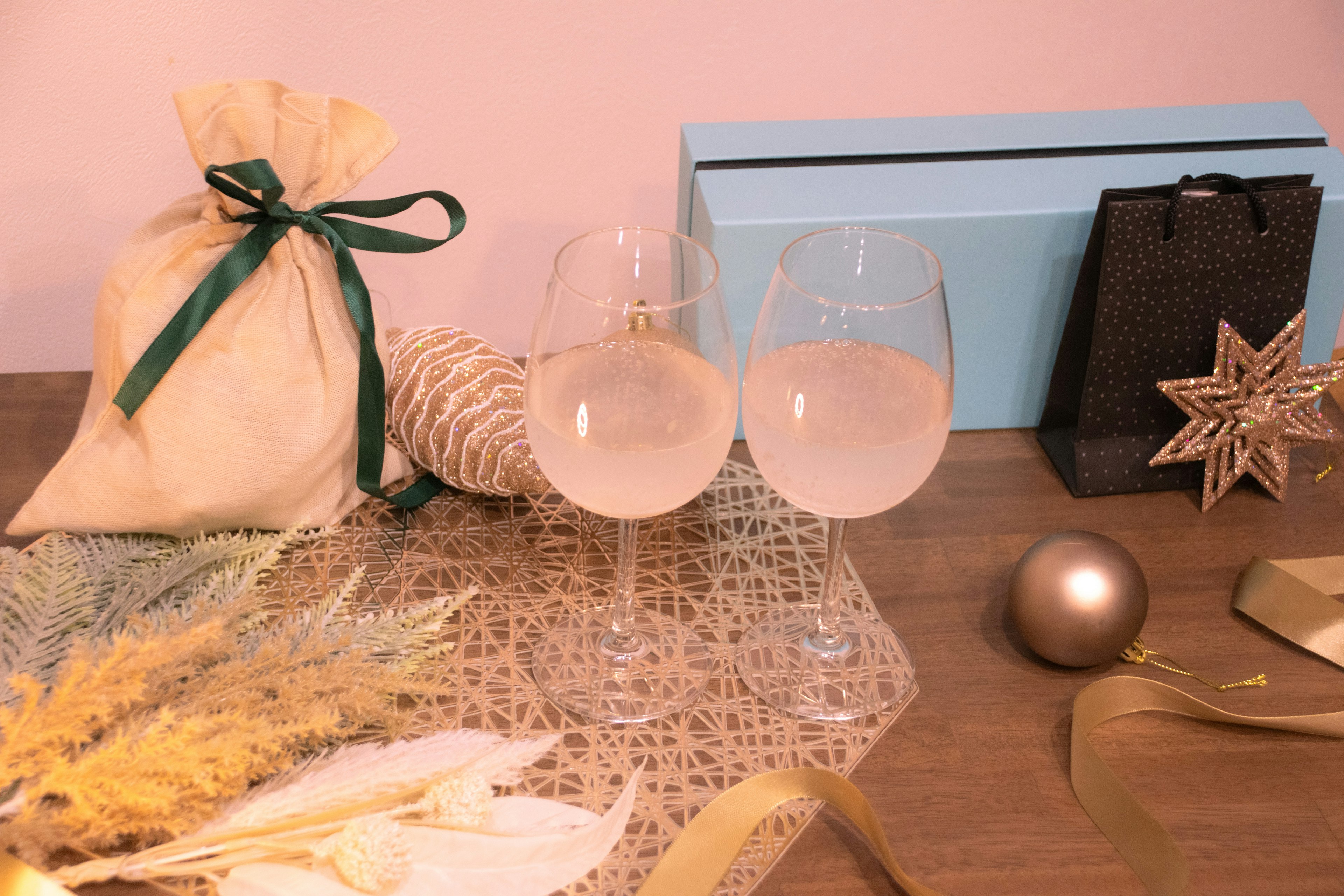 Deux verres sur une table décorée pour Noël avec un sac cadeau et des ornements