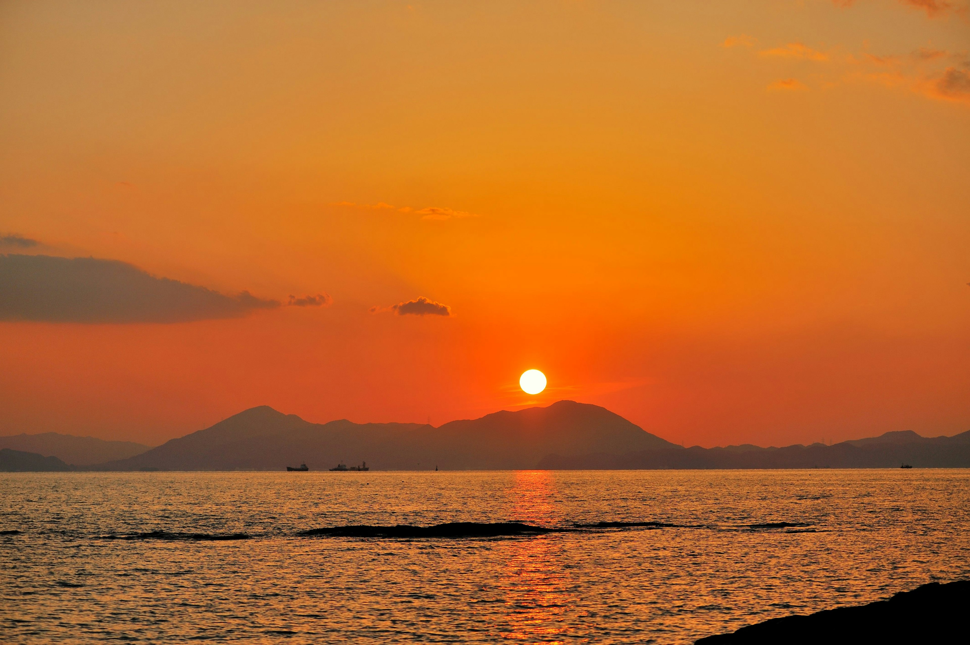 Orangenes Sonnenuntergang über dem Meer mit Bergsilhouetten