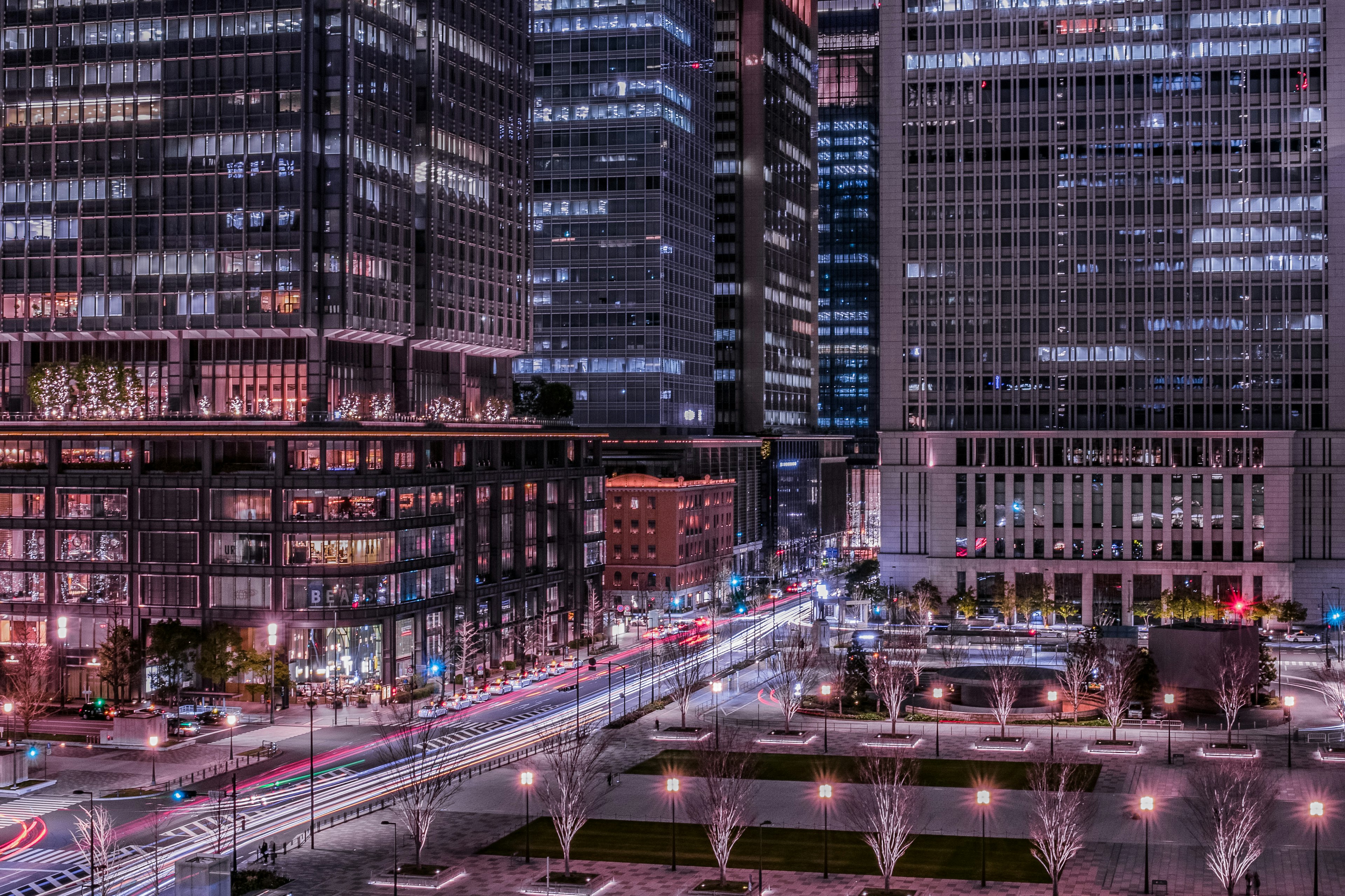 Night cityscape featuring tall buildings light trails across the road vibrant colors