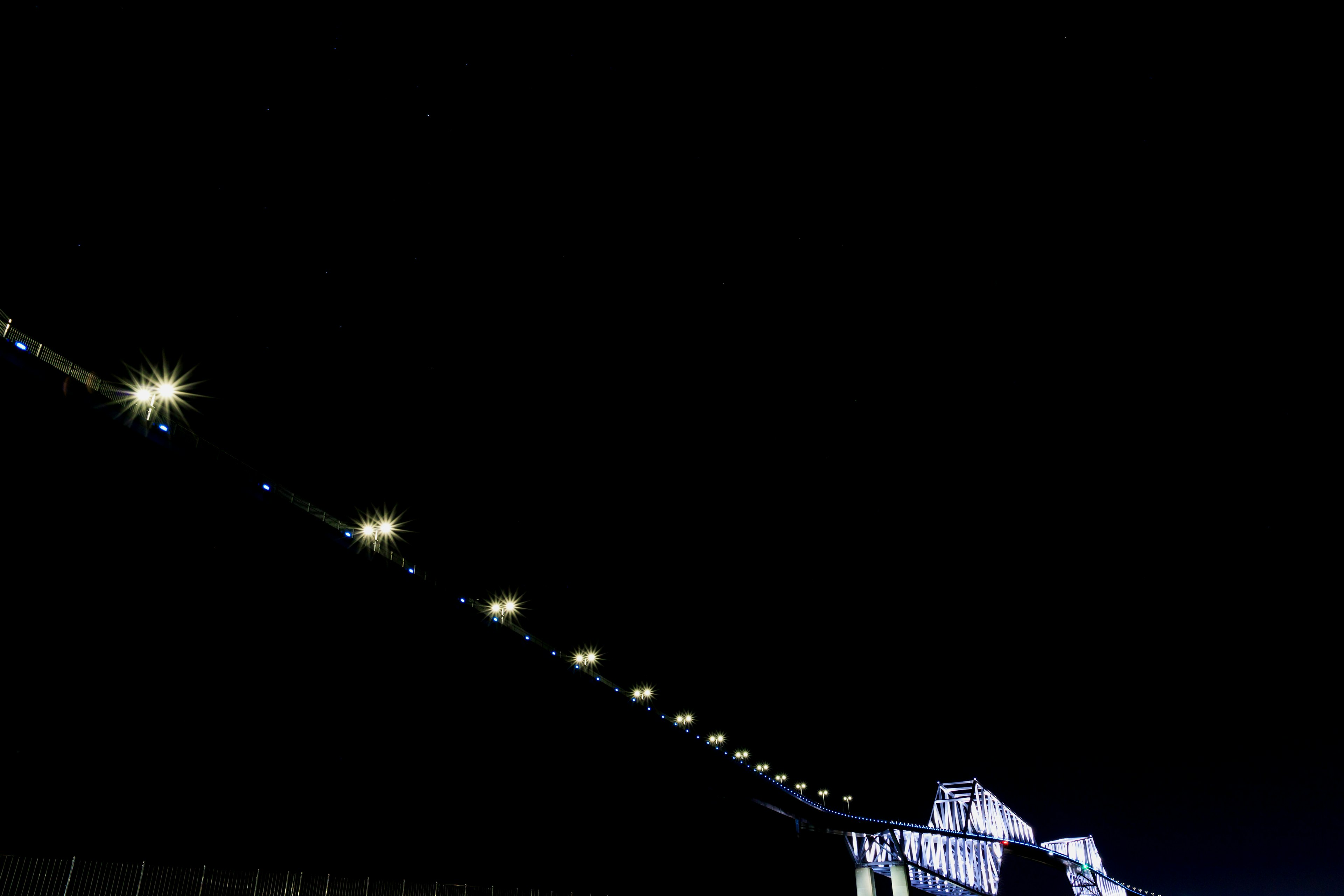 A long bridge illuminated by lights against a dark sky