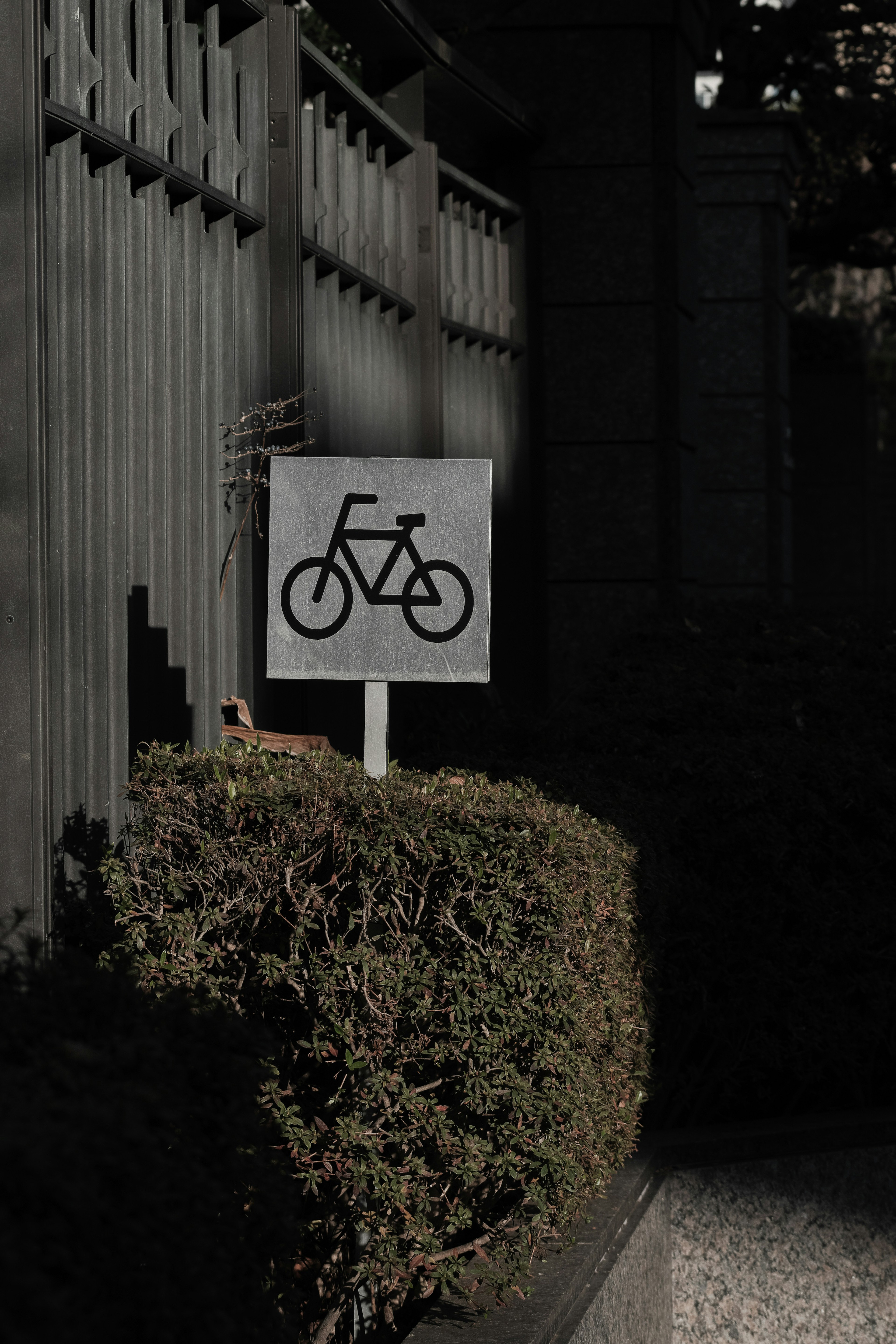 Ein Schild mit einem Fahrradsymbol steht in der Nähe eines grünen Zauns