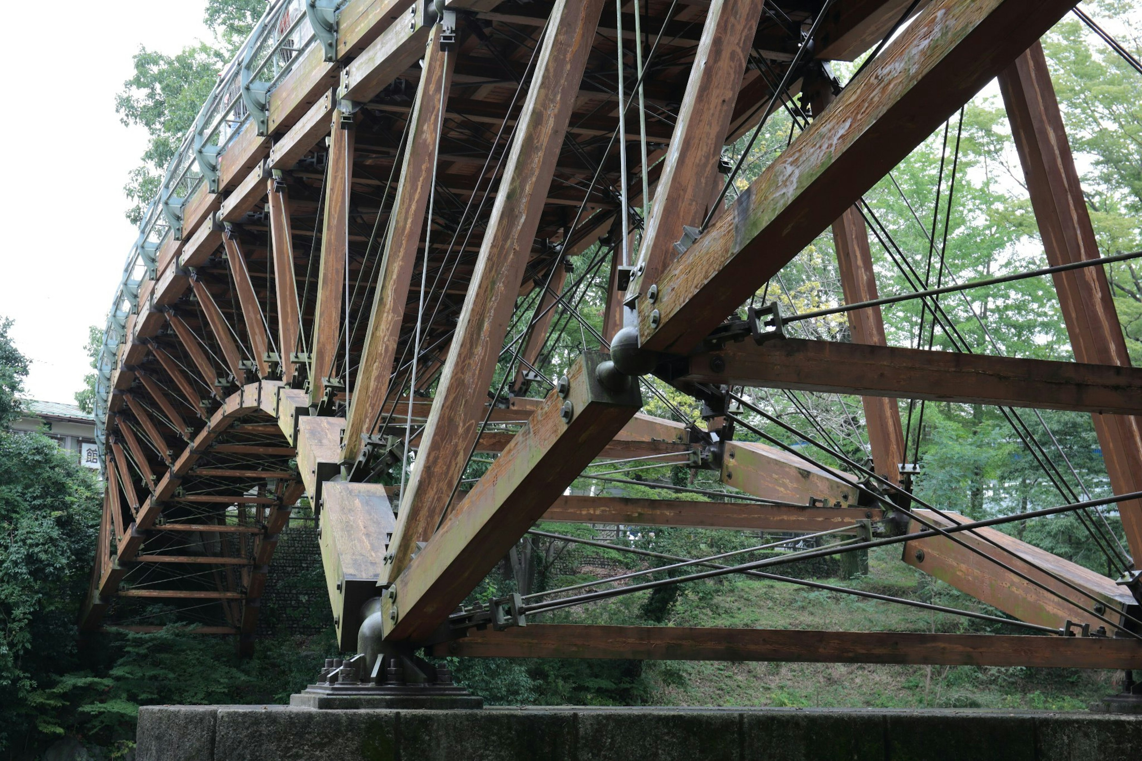 Vista de una estructura de puente de arco de madera sostenida por cables y vigas