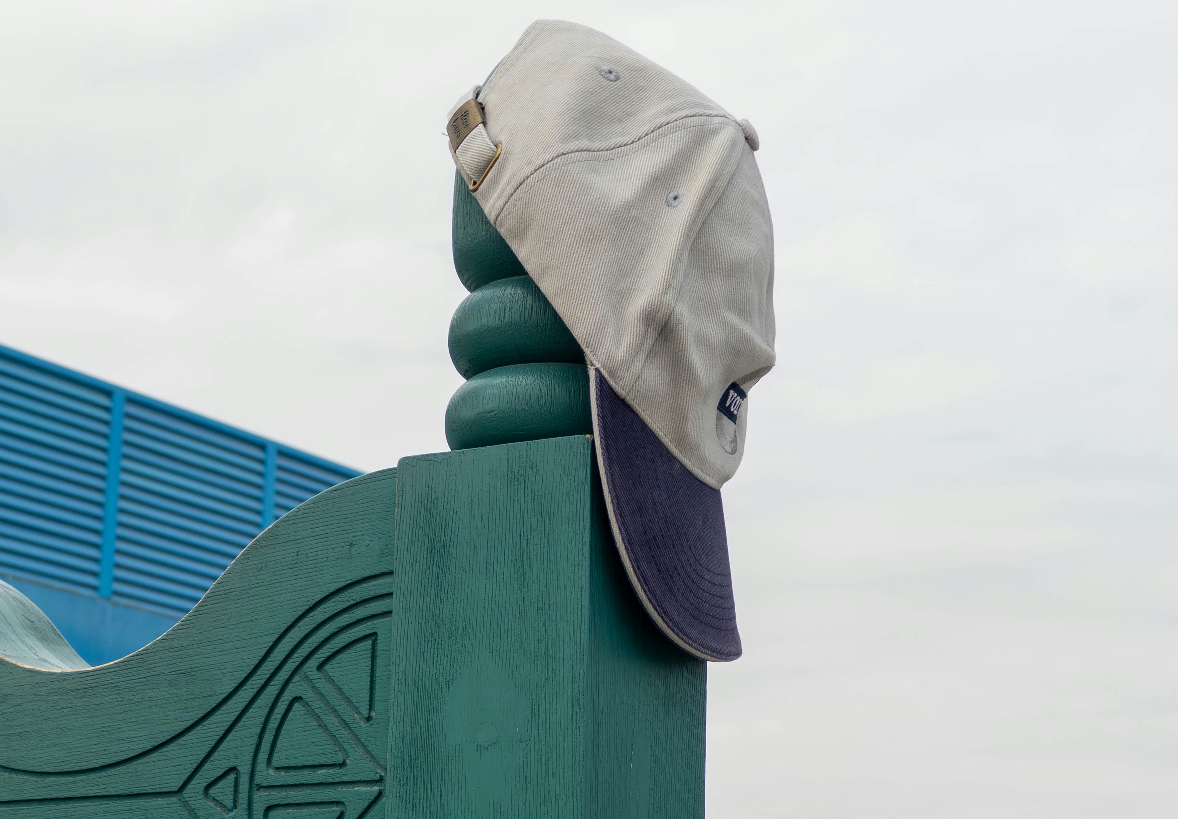 Casquette accrochée à un poteau vert avec un fond bleu