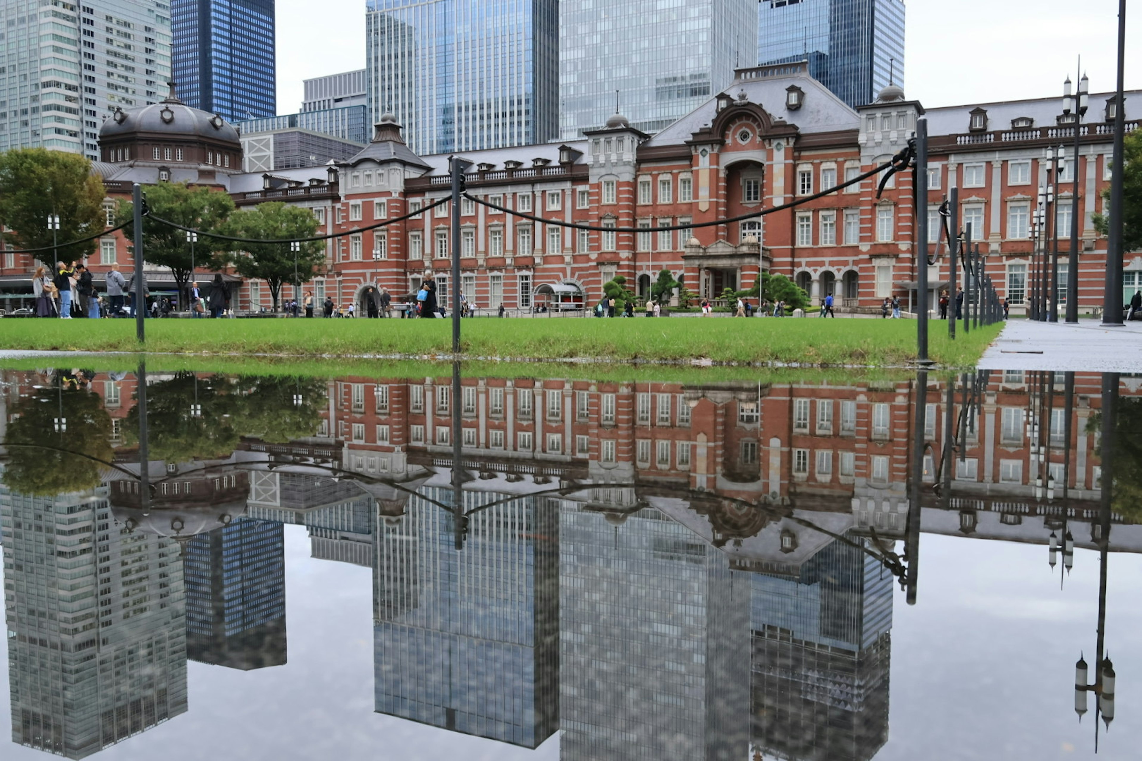 Reflejo del edificio de ladrillo rojo de la estación de Tokio en un charco