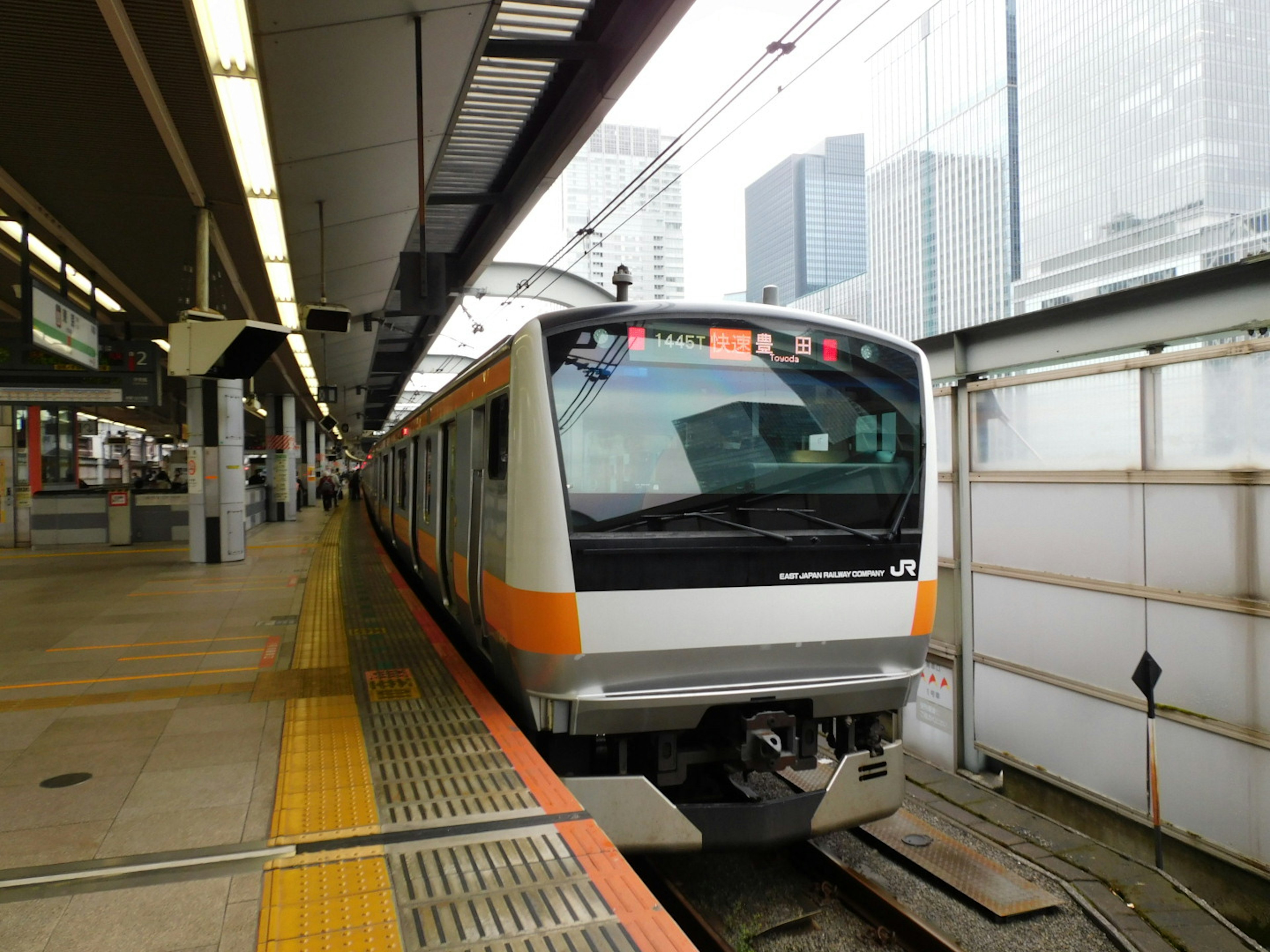 Train with orange stripes stopped at a station platform