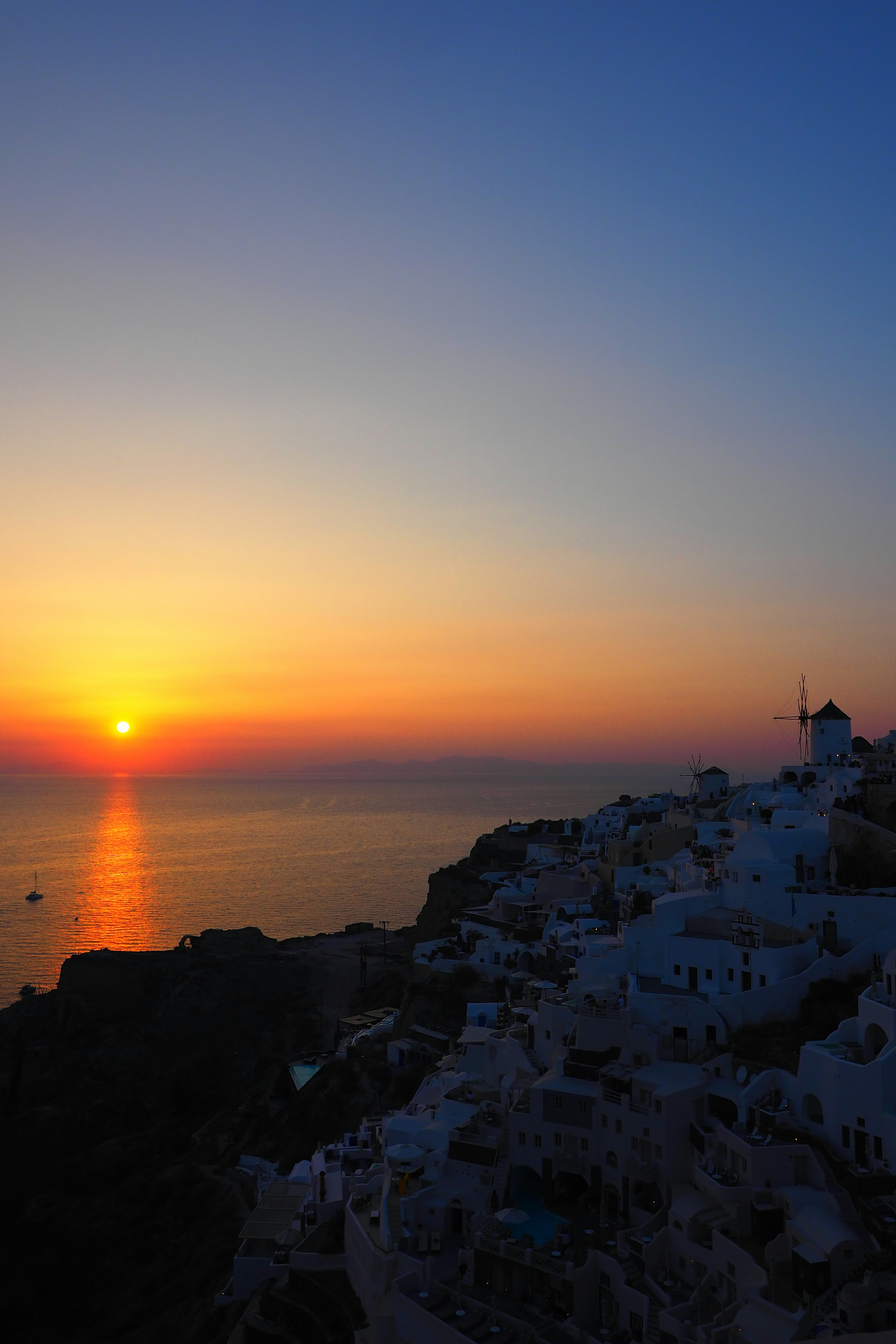 Pemandangan indah Santorini dengan matahari terbenam di atas laut dan bangunan putih