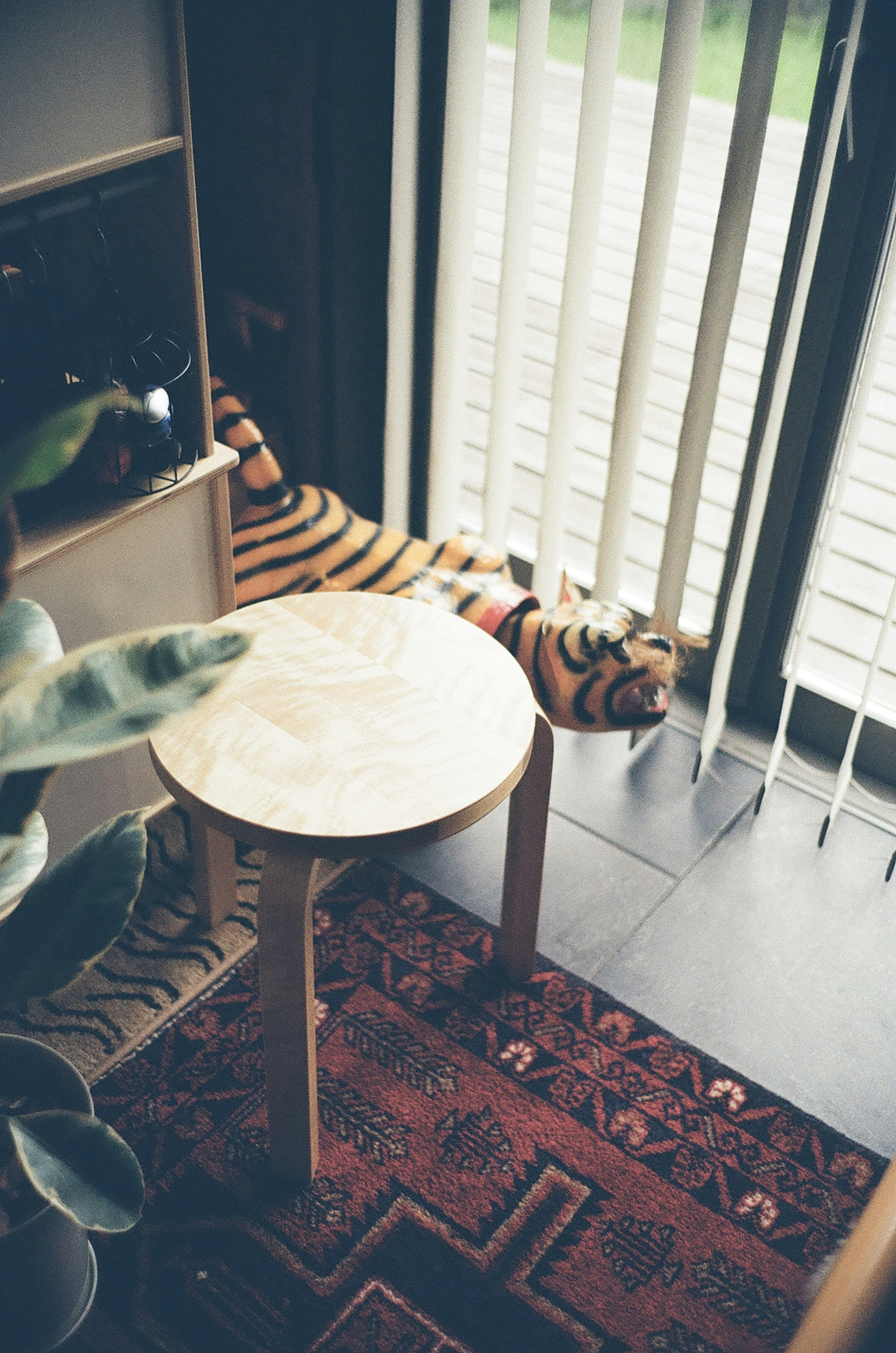 A striped tiger plush toy lying in front of a wooden table with a round marble top