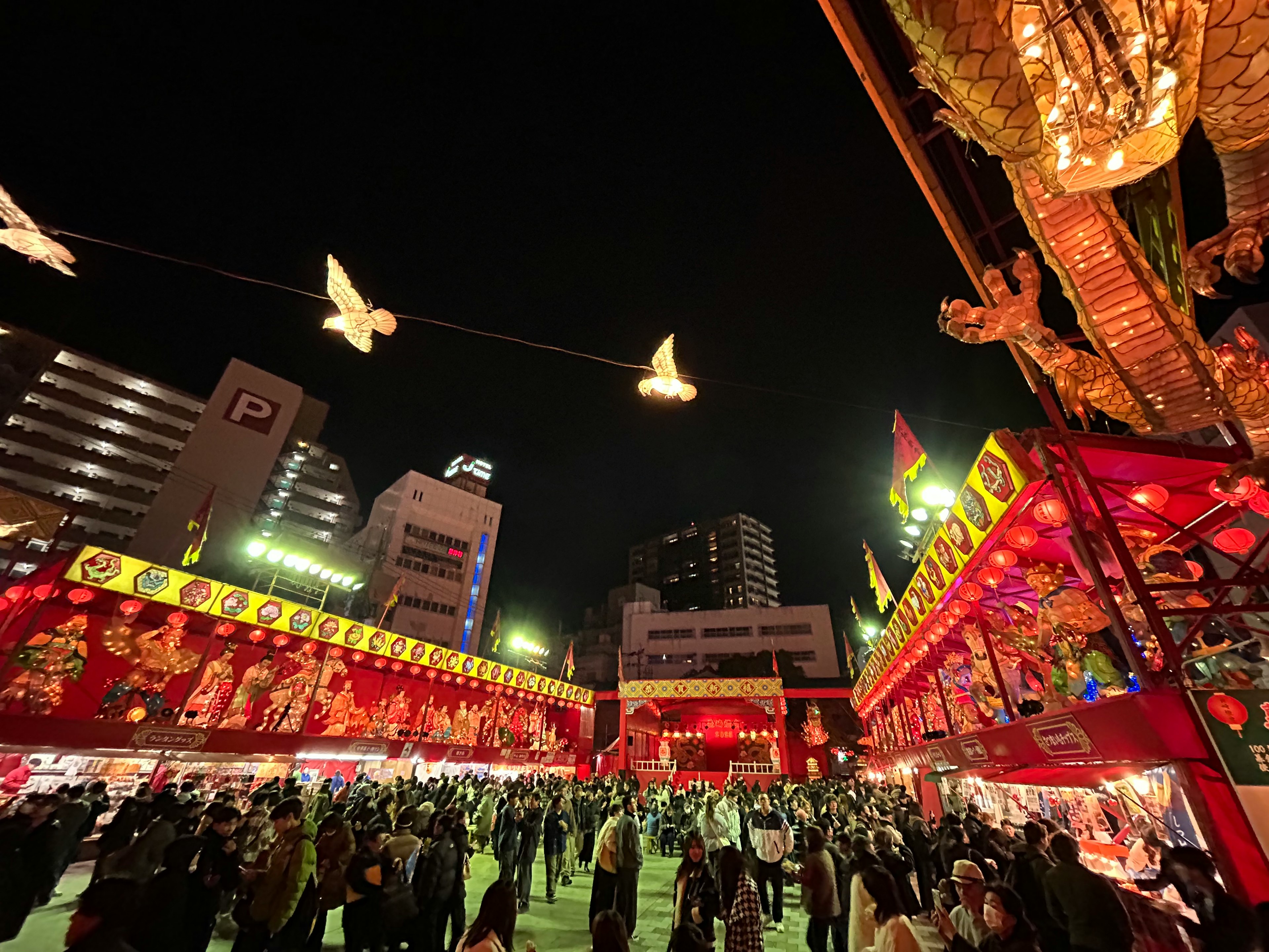 Festival nocturne vibrant avec des stands décorés en rouge et des oiseaux illuminés