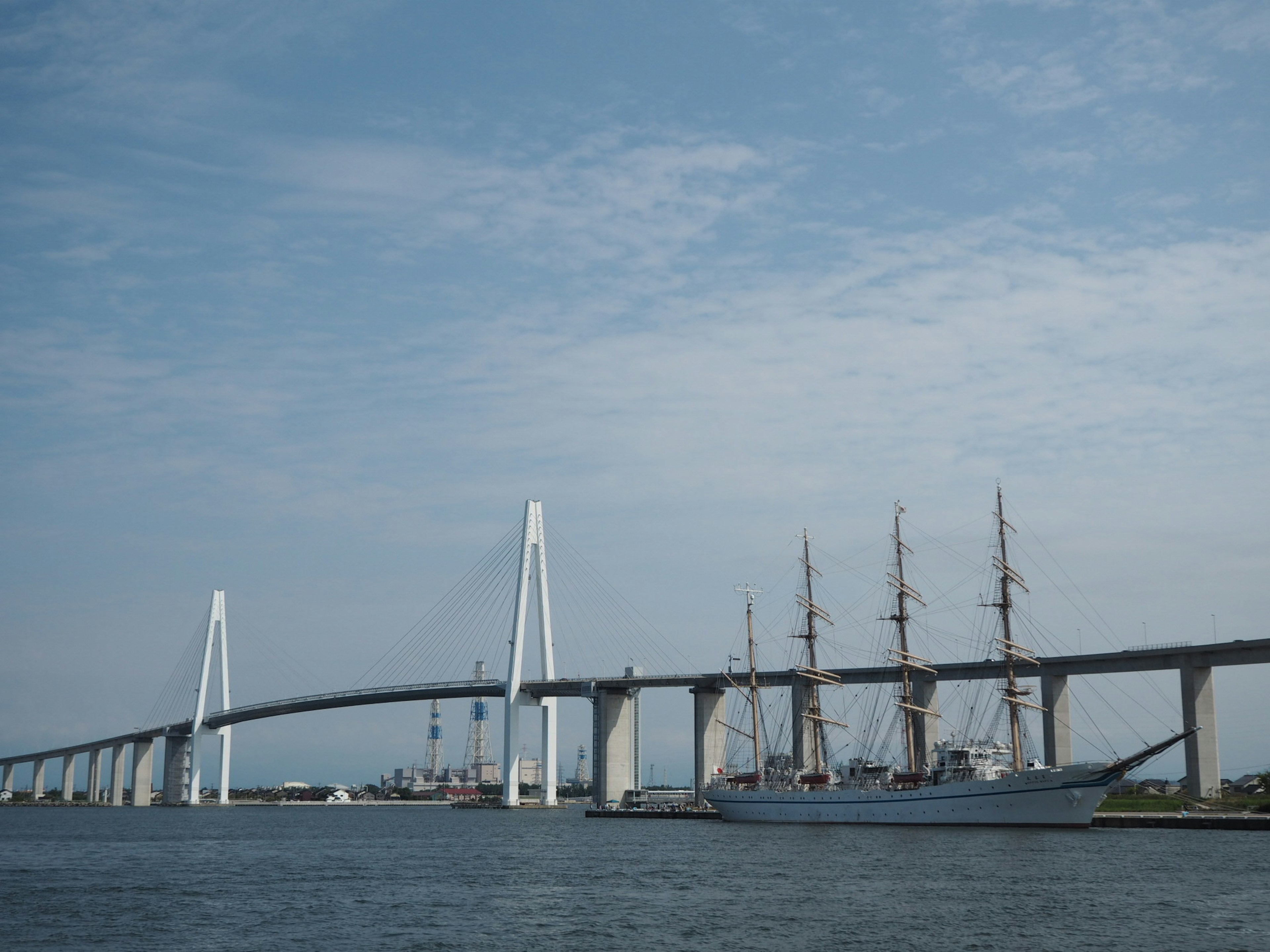 View of a bridge and a sailing ship under a blue sky