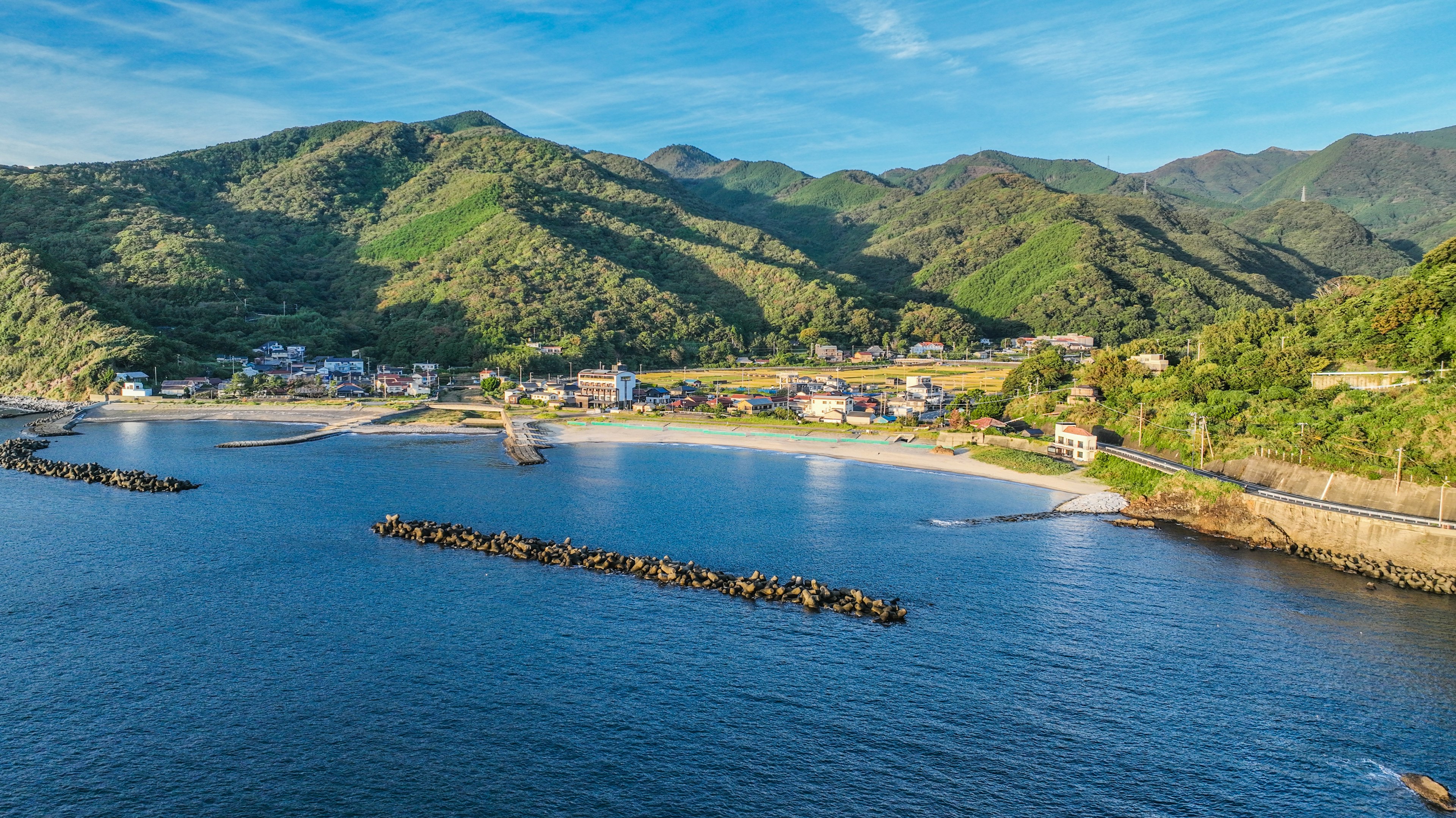 Scenic view of a tranquil bay surrounded by lush green mountains and blue sea