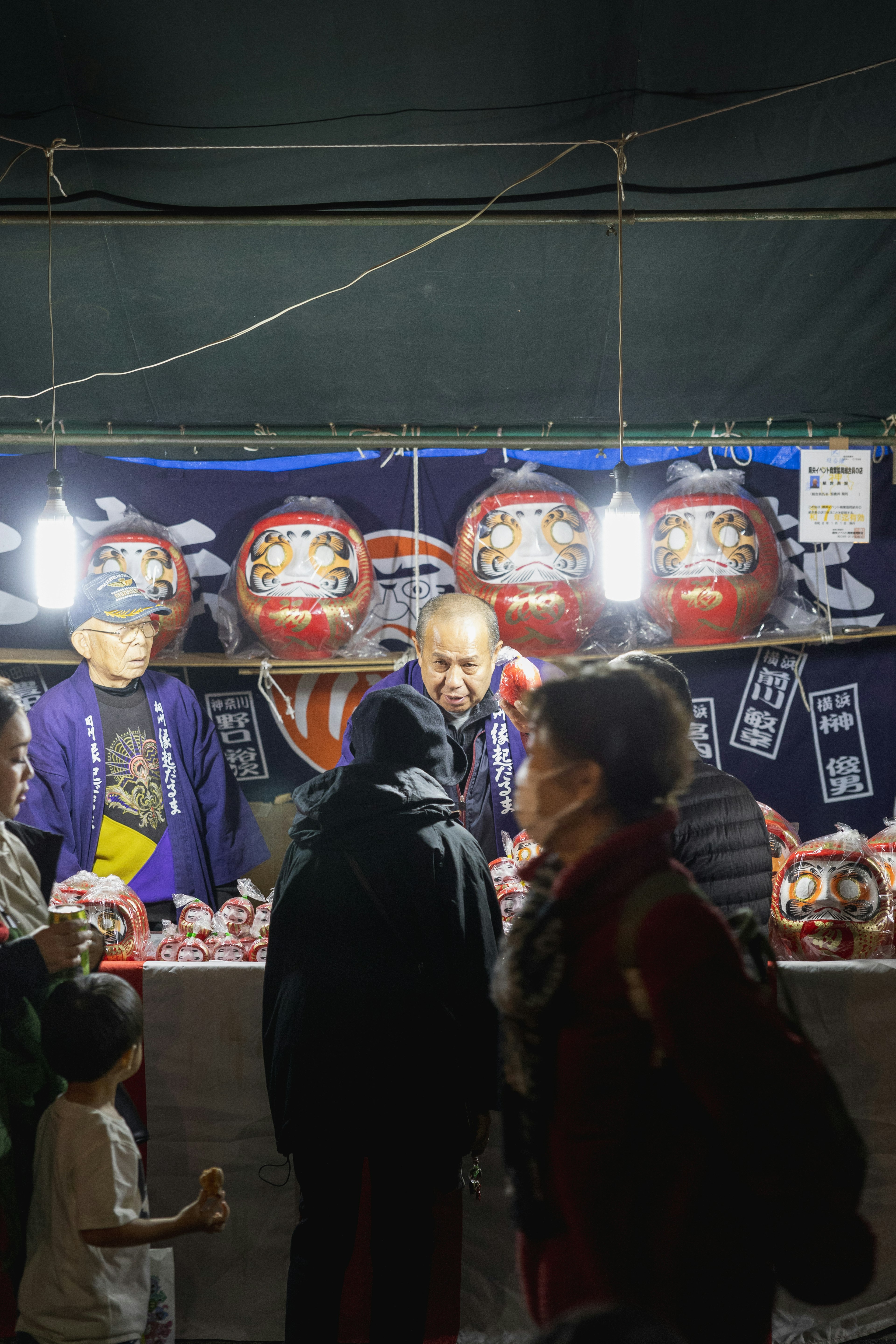 Photo of people selling Daruma dolls at a market stall