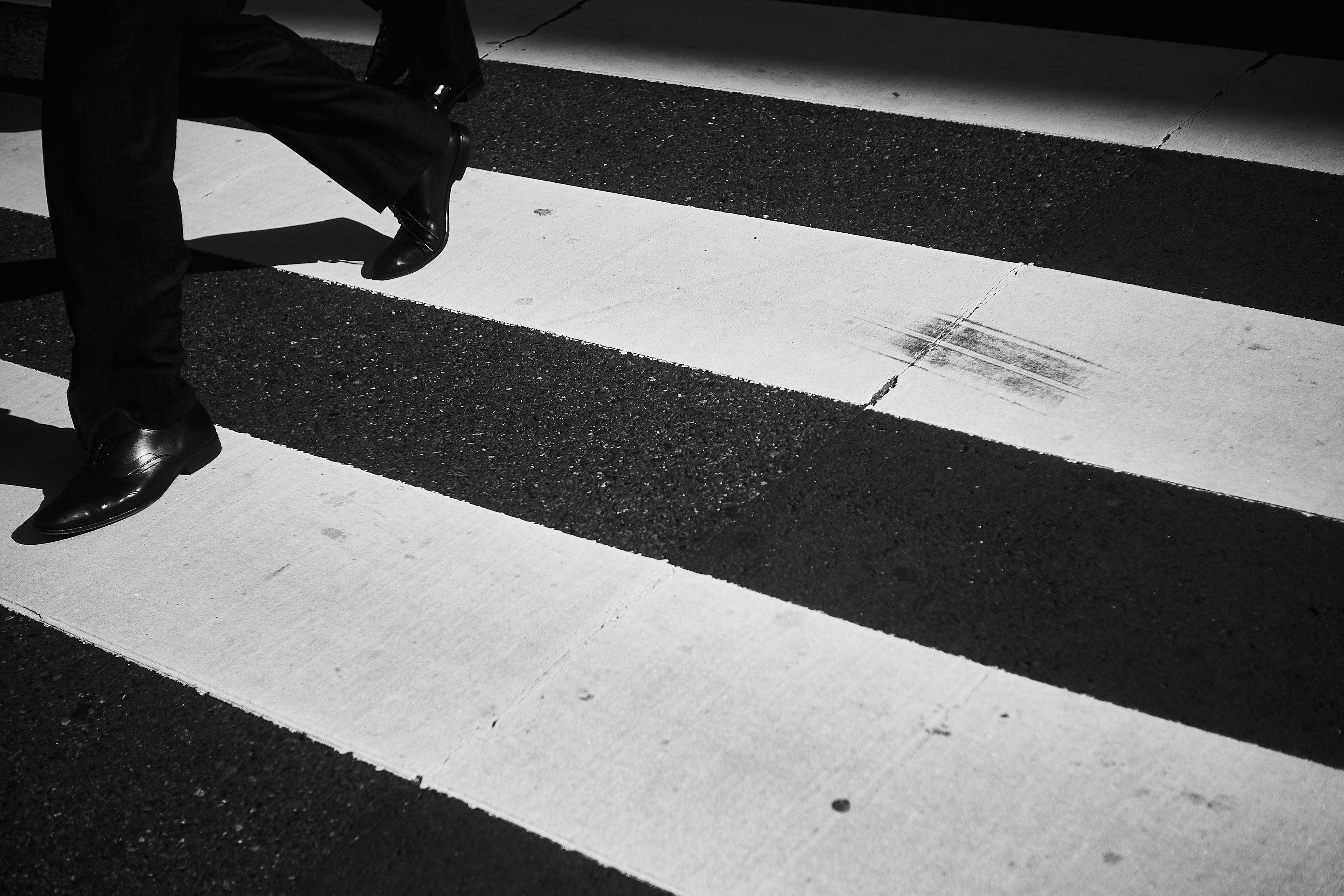 A businessman walking across a black and white crosswalk