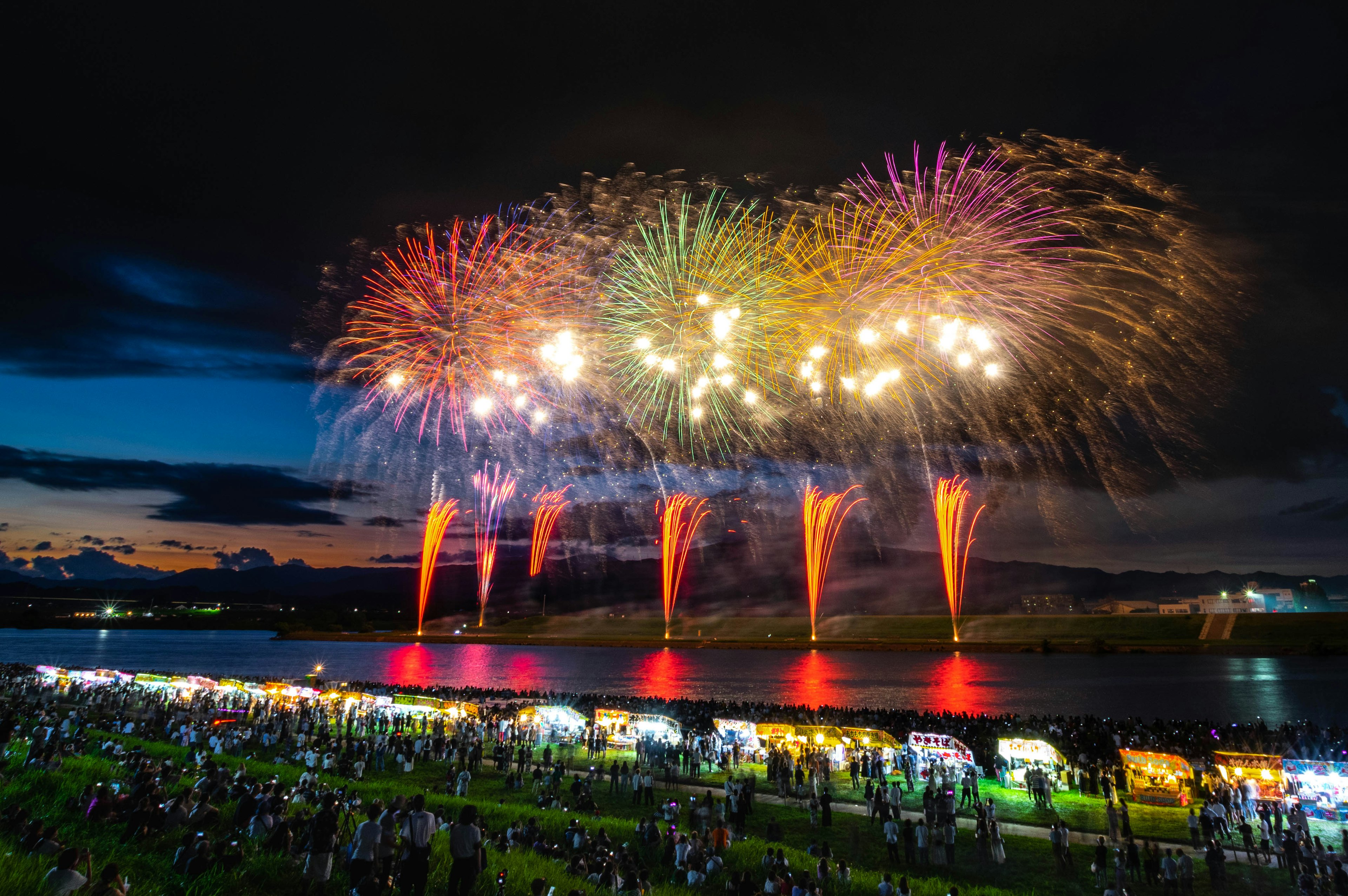 Espectáculo de fuegos artificiales en el cielo nocturno con siluetas de espectadores