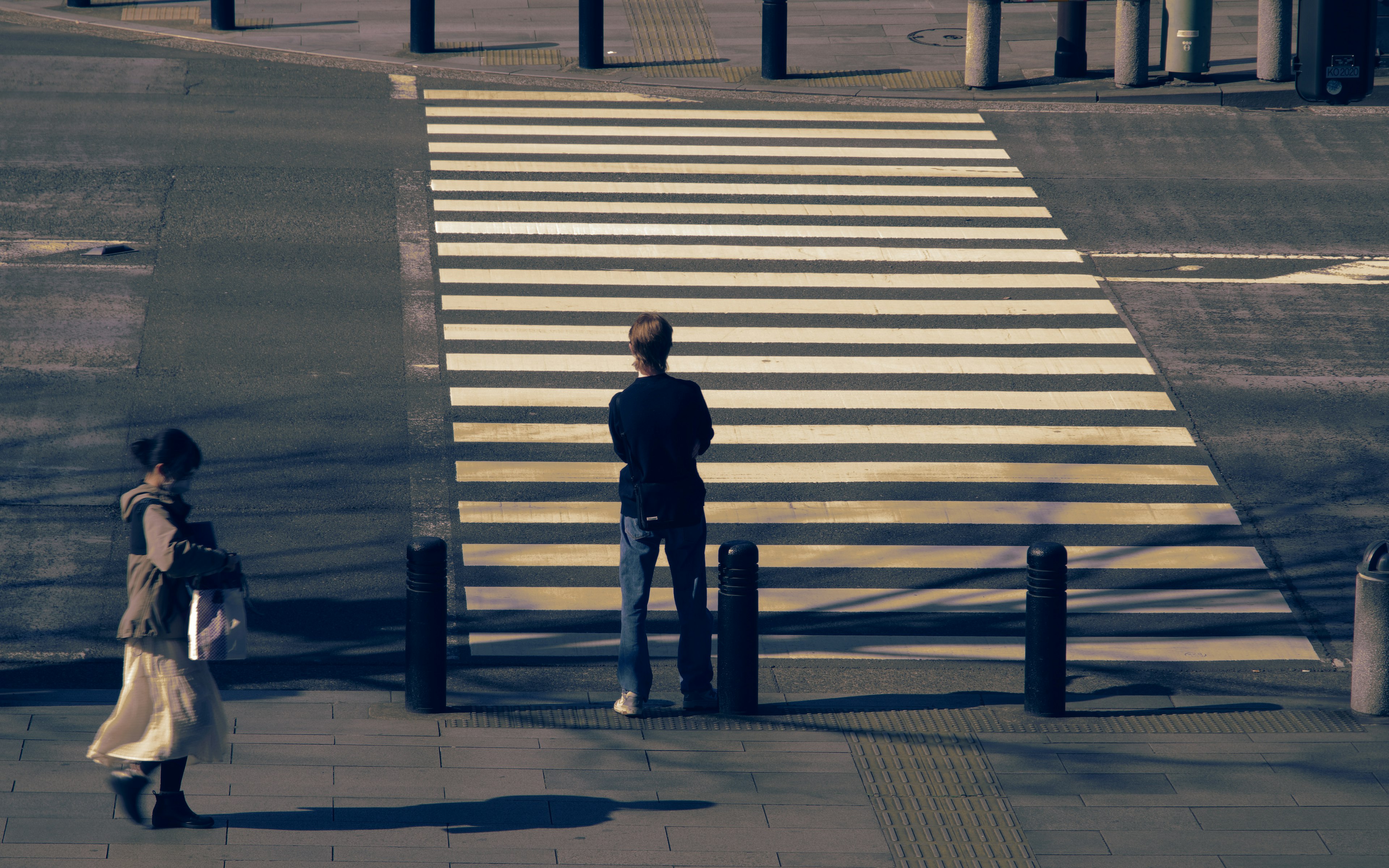 Pria berdiri di depan zebra cross dengan wanita di dekatnya