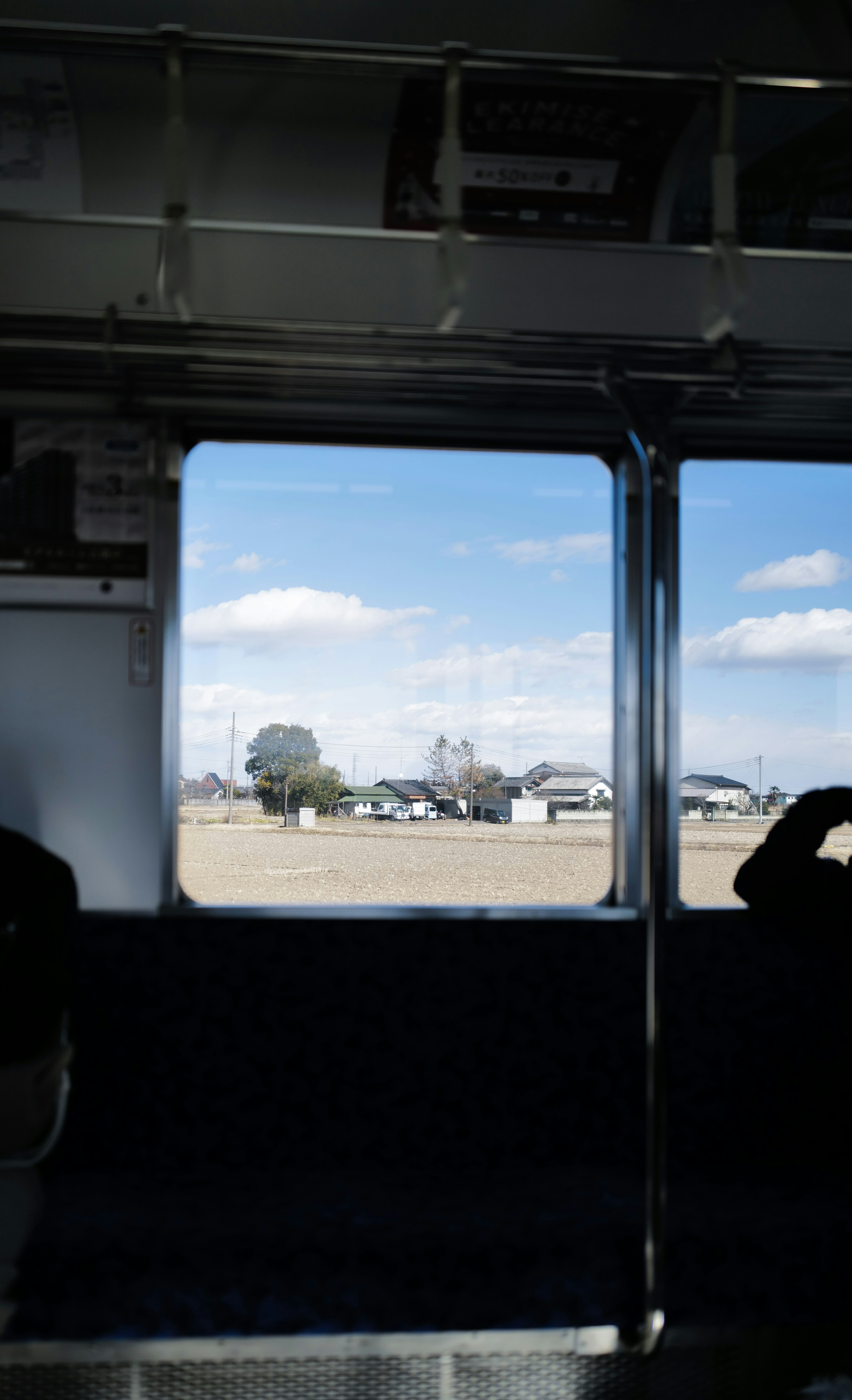 Vista da una finestra del treno che mostra cielo blu e nuvole bianche