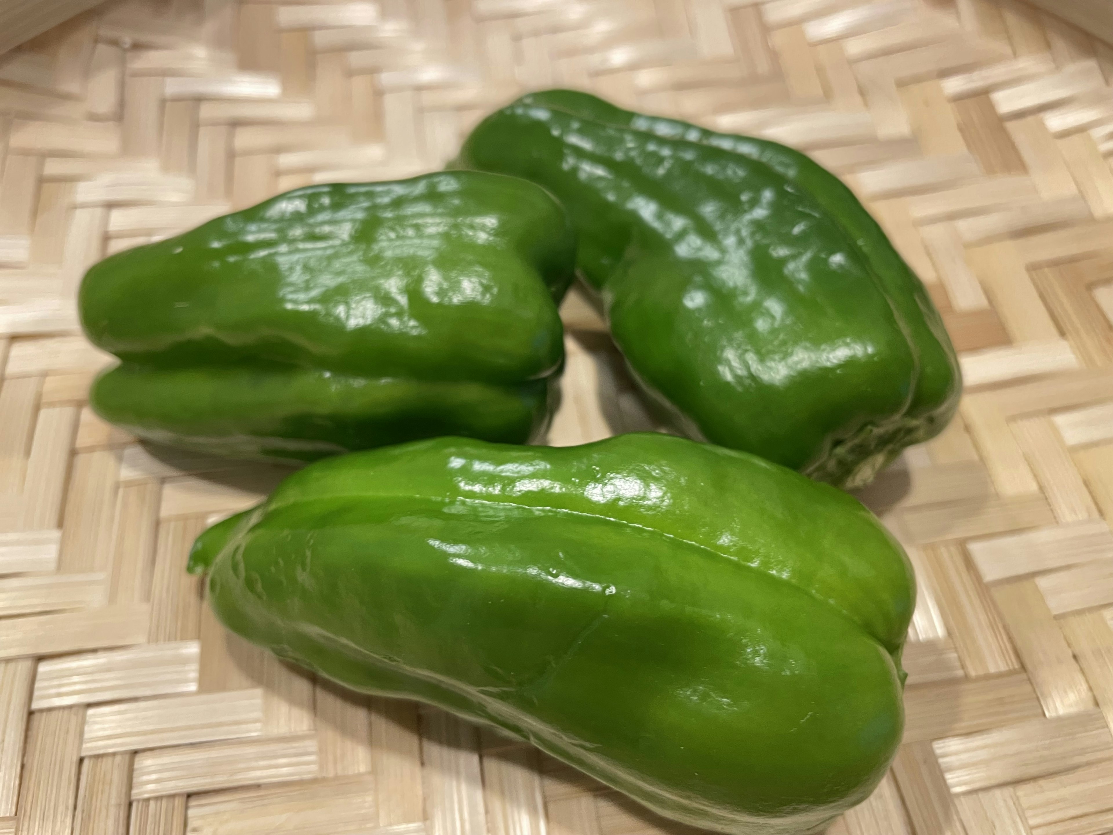 Three green vegetables placed on a woven bamboo surface