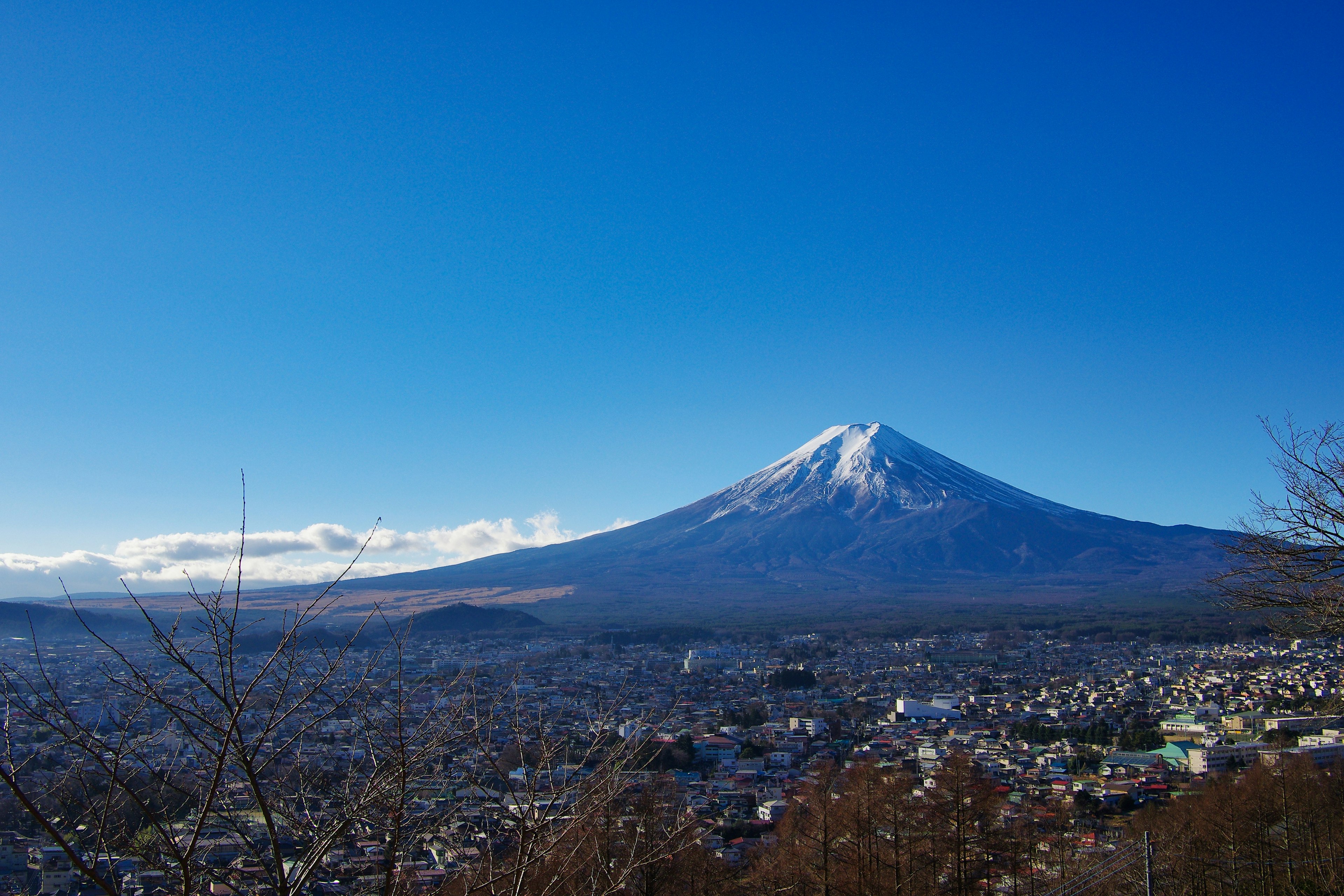 Gunung Fuji menjulang di bawah langit biru cerah dengan pemandangan kota di sekitarnya