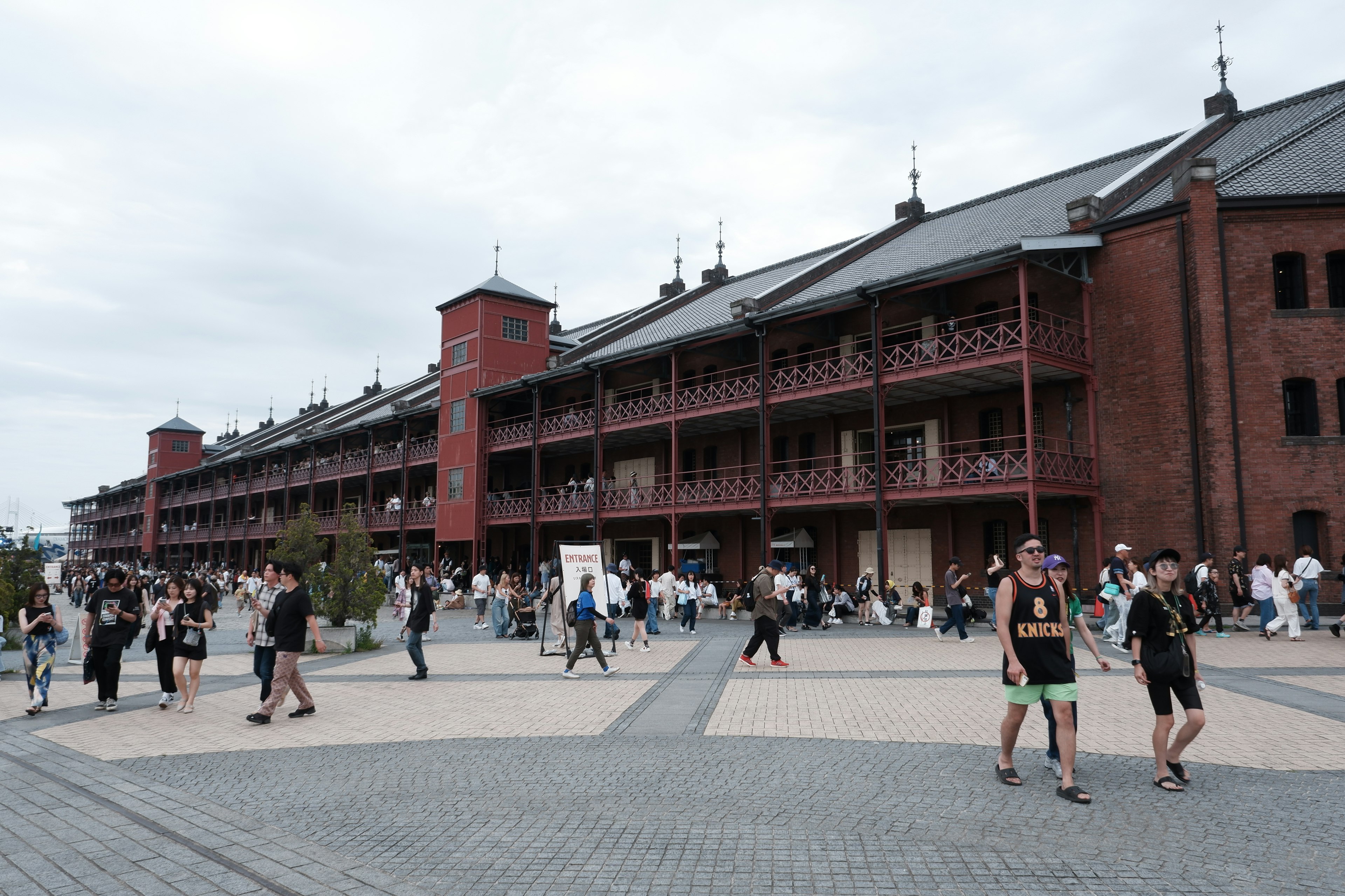 People walking in front of red brick warehouse and surrounding scenery