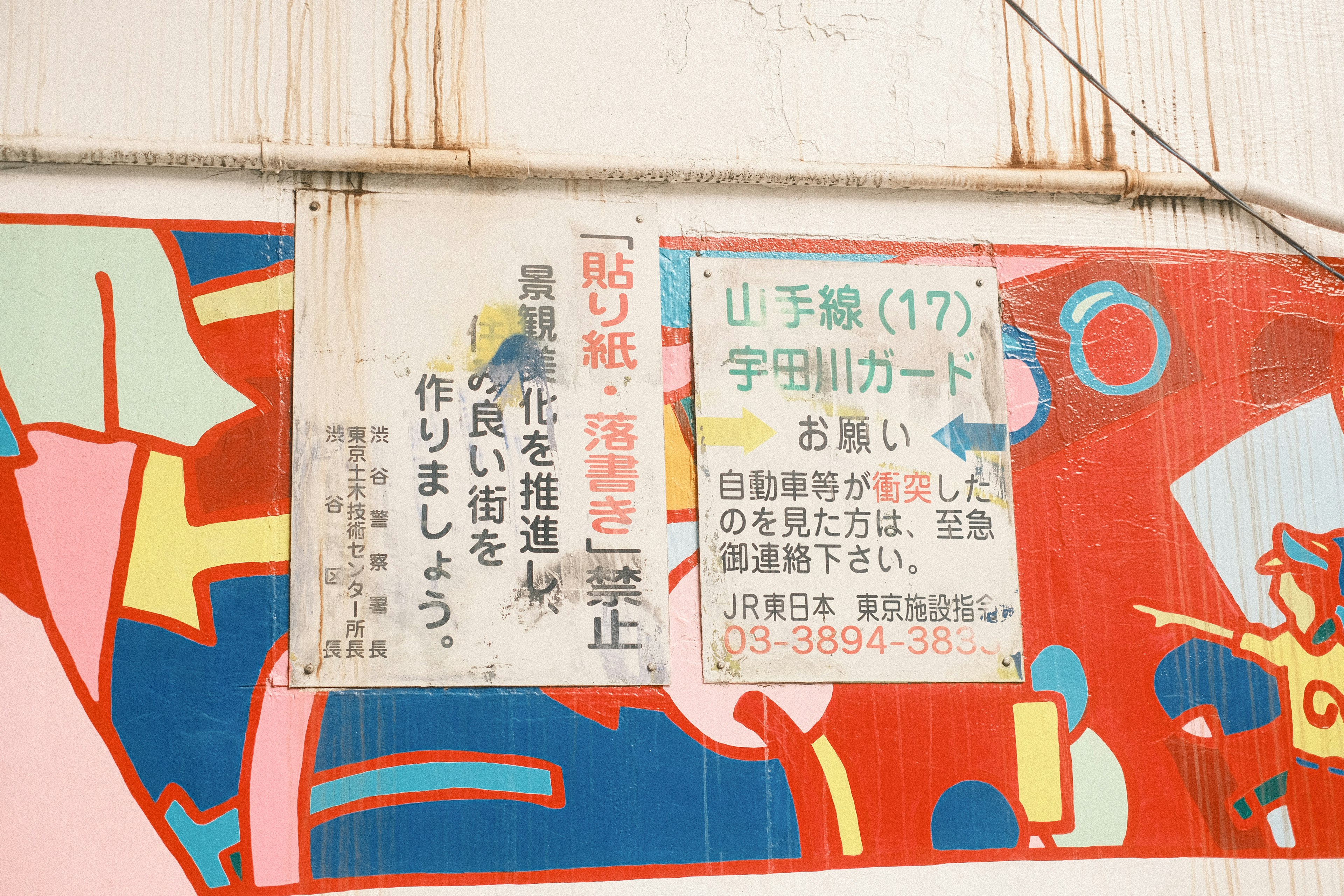 A colorful mural featuring a Japanese sign discussing community development and prevention of vandalism