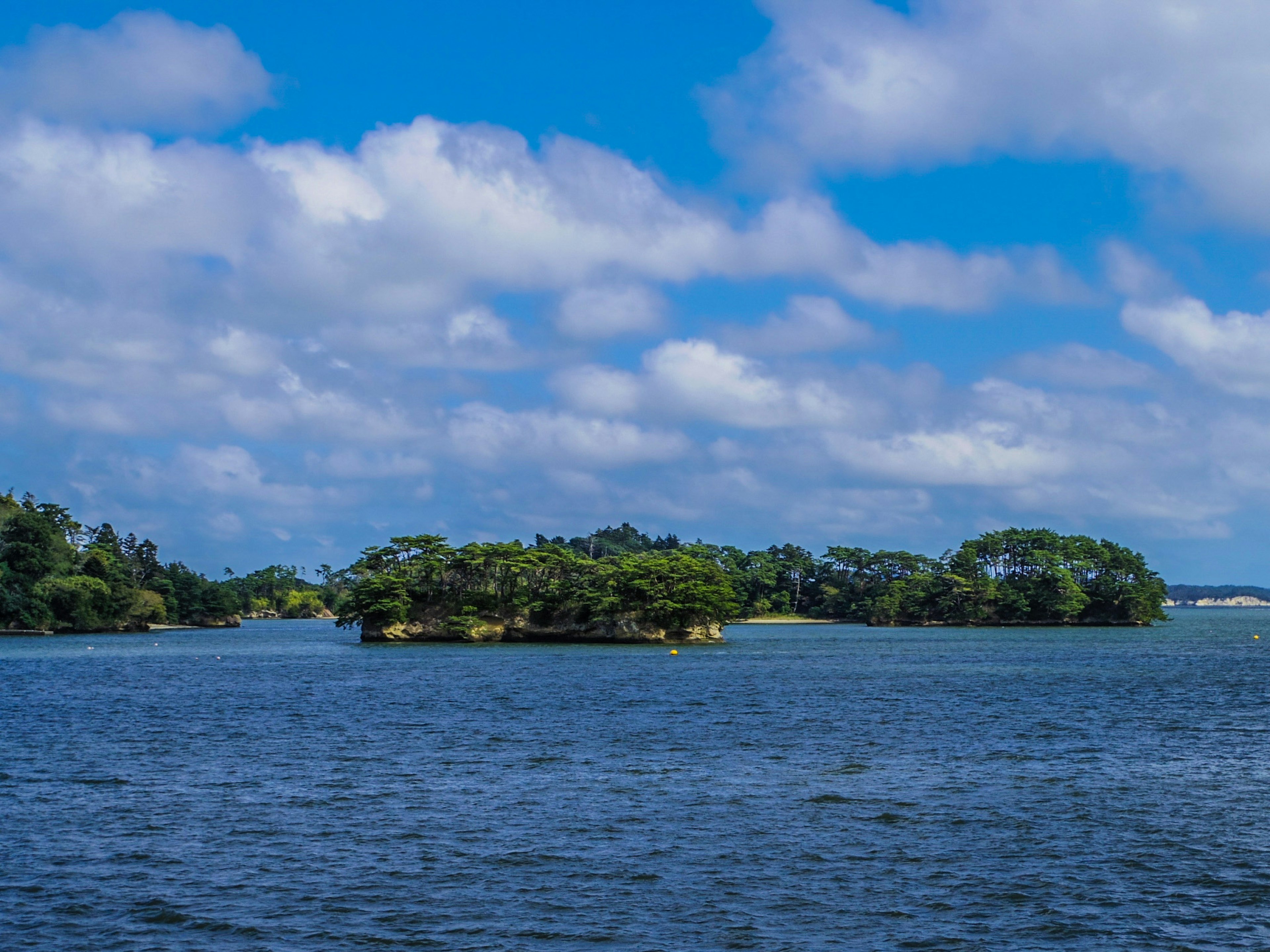 Isole circondate da un cielo blu e nuvole bianche in un lago sereno