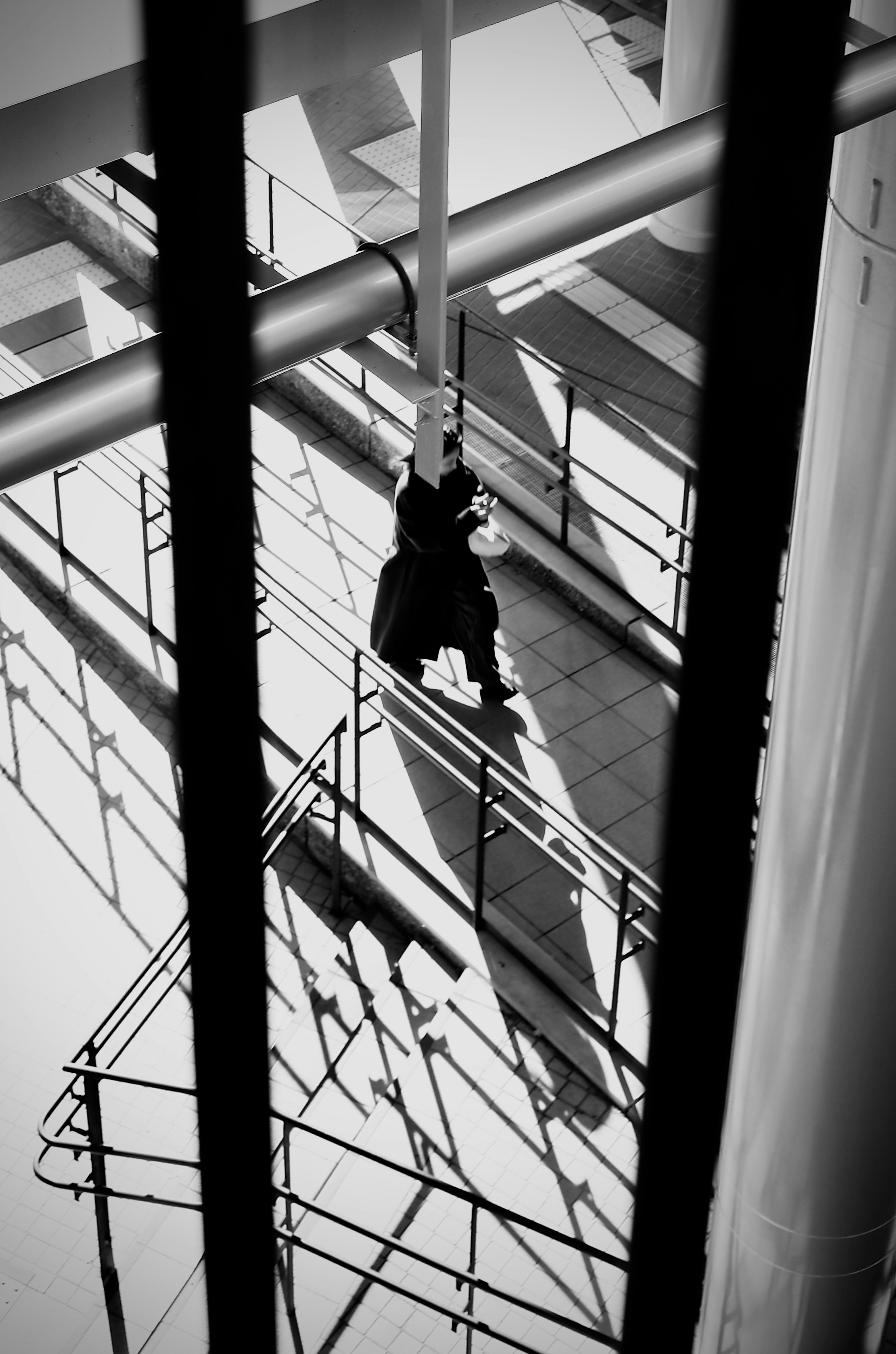 Black and white photo of a person descending stairs with strong contrasts of shadows and light