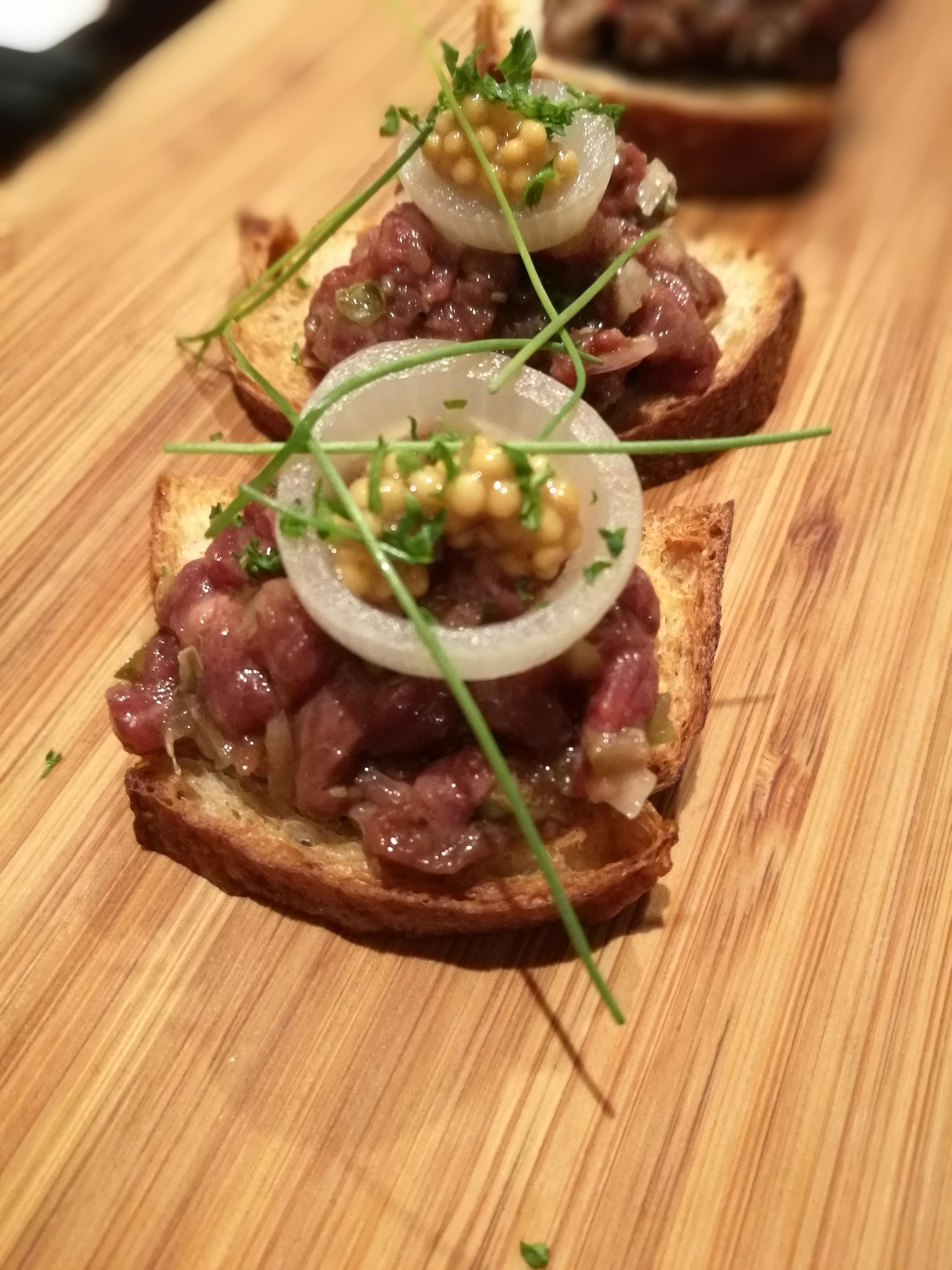 Close-up of toasted bread topped with minced meat and garnished with herbs