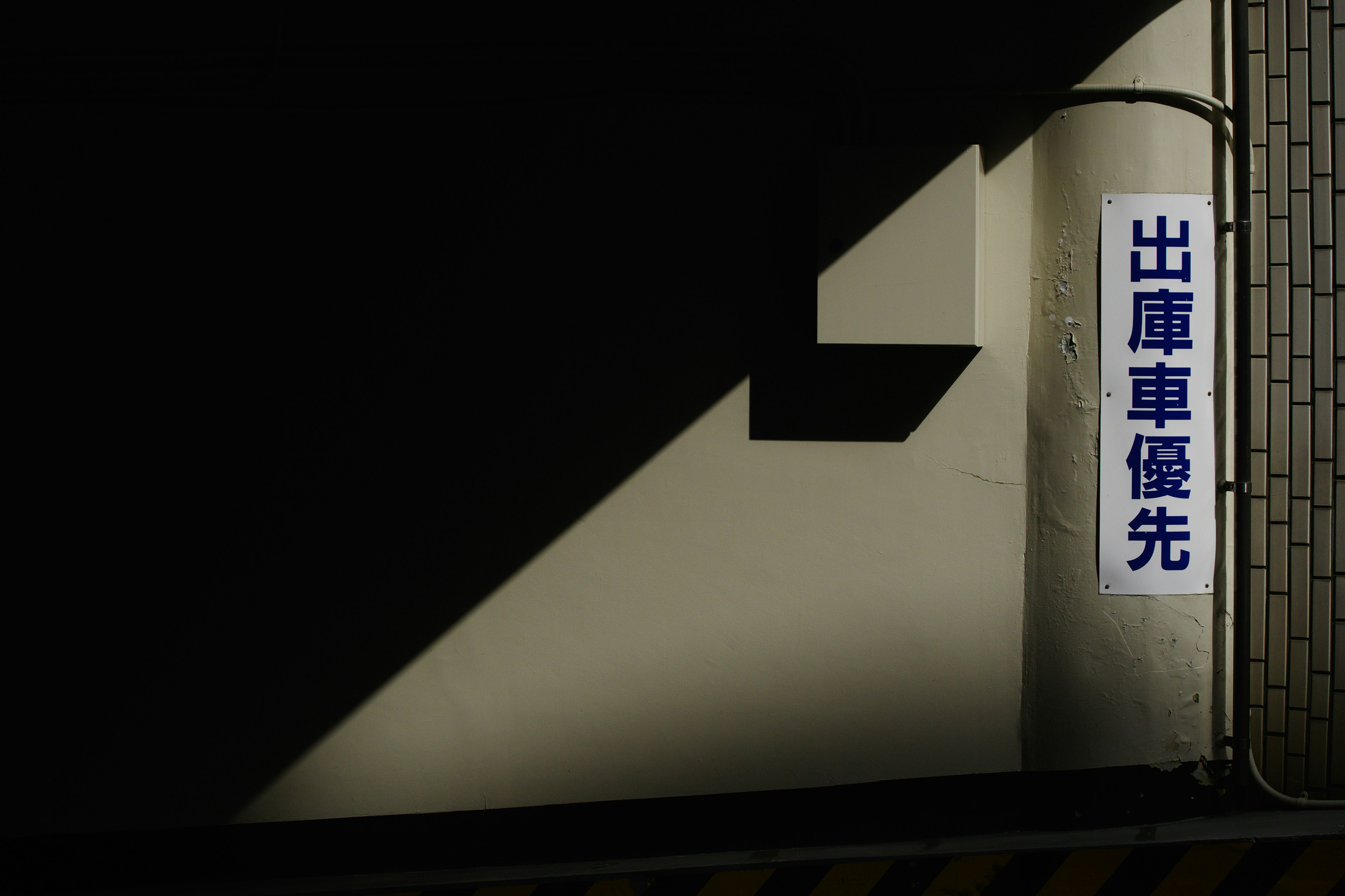 Japanese sign on a wall with shadows and light contrast