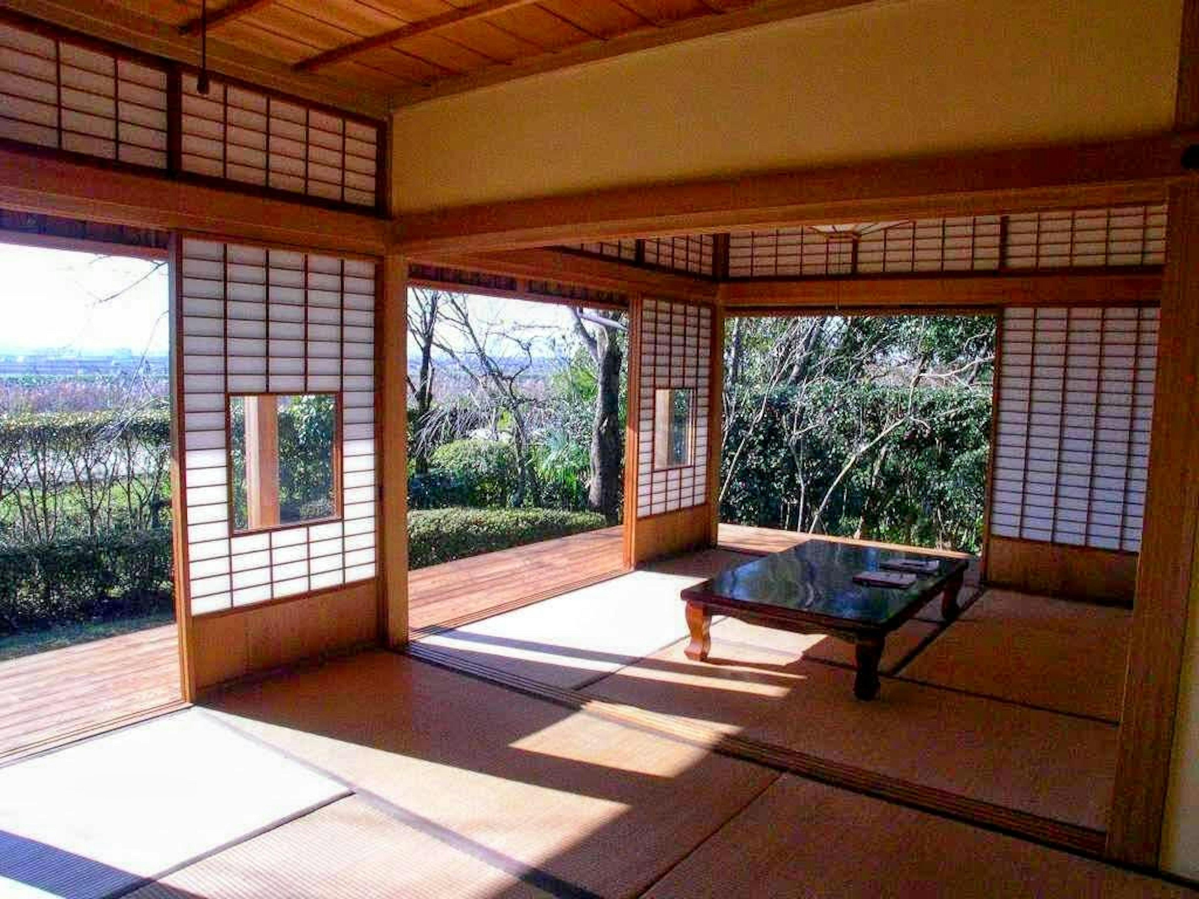 Interior of a traditional Japanese room with wooden table and shoji windows showing an outdoor view