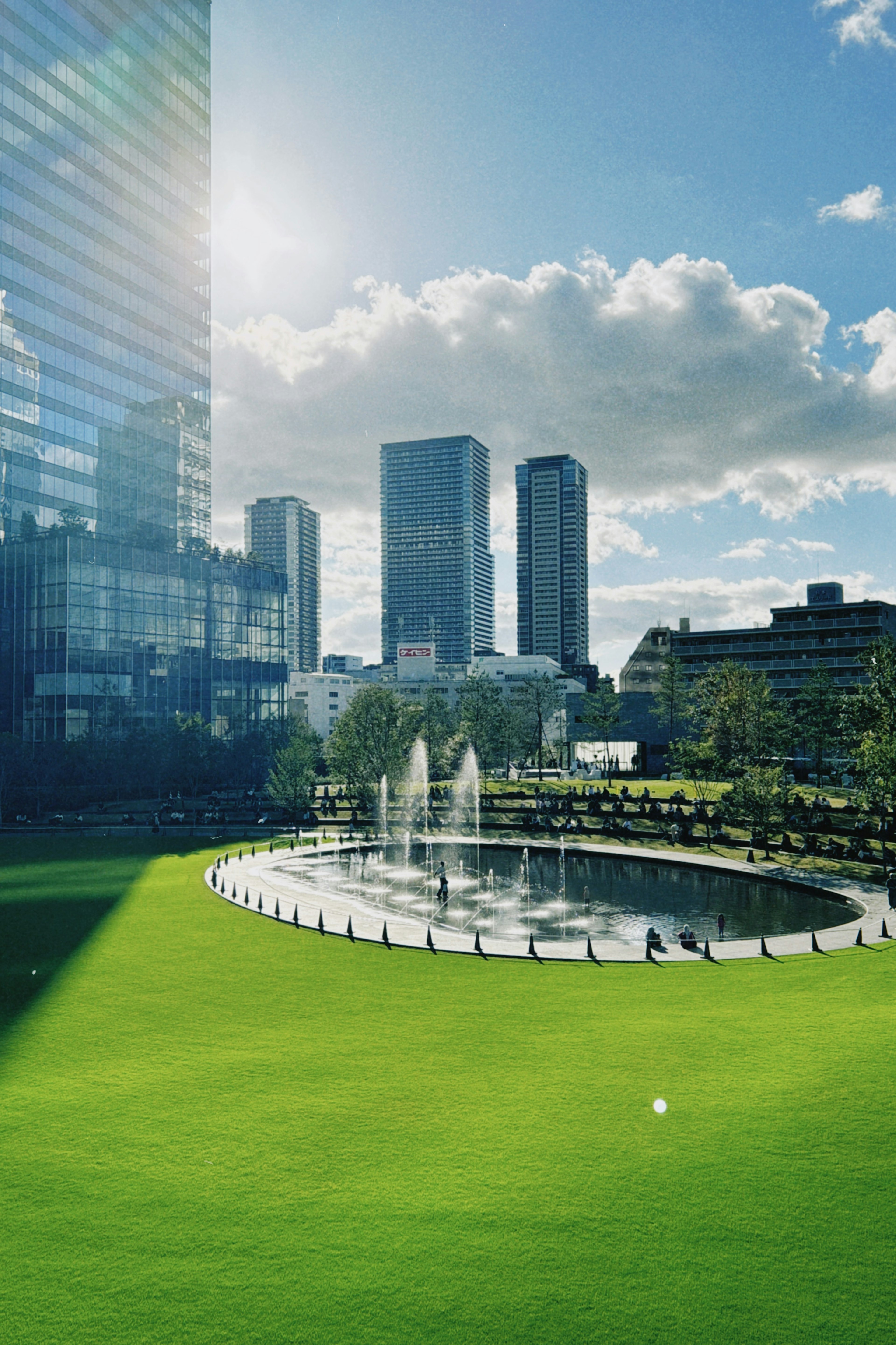 Un parc pittoresque avec de l'herbe verte un étang et des bâtiments élevés sous un ciel bleu