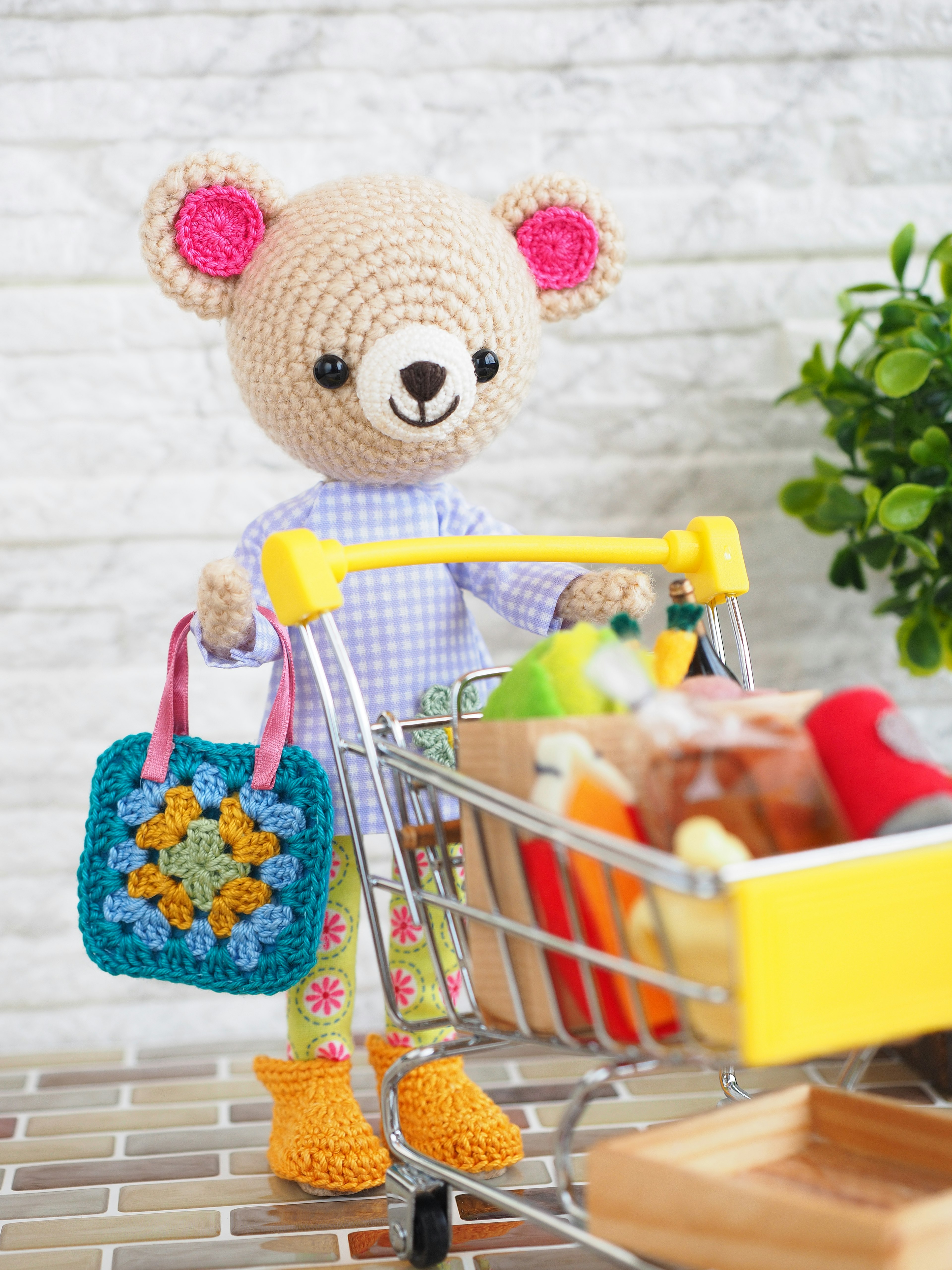 Un adorable ours en peluche portant un panier de courses coloré et un chariot rempli de produits alimentaires vibrants