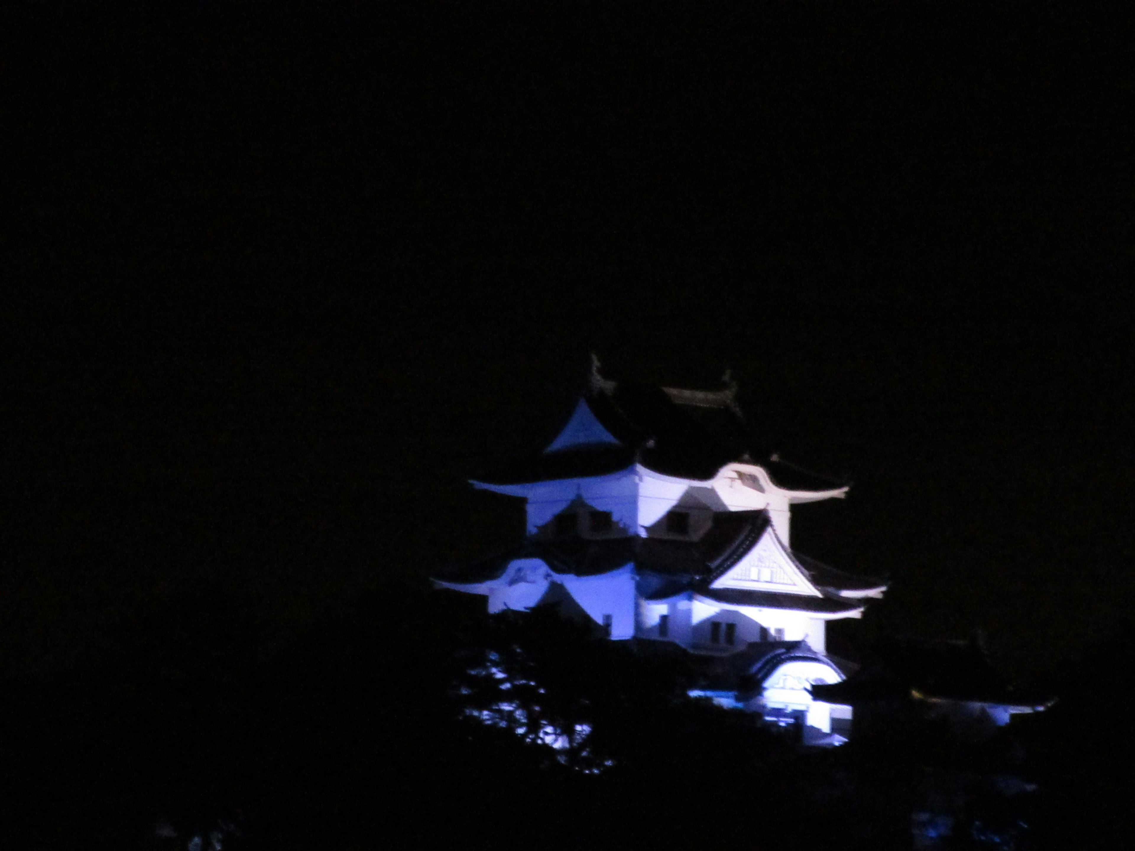 Siluet kastil Jepang yang diterangi cahaya biru di malam hari